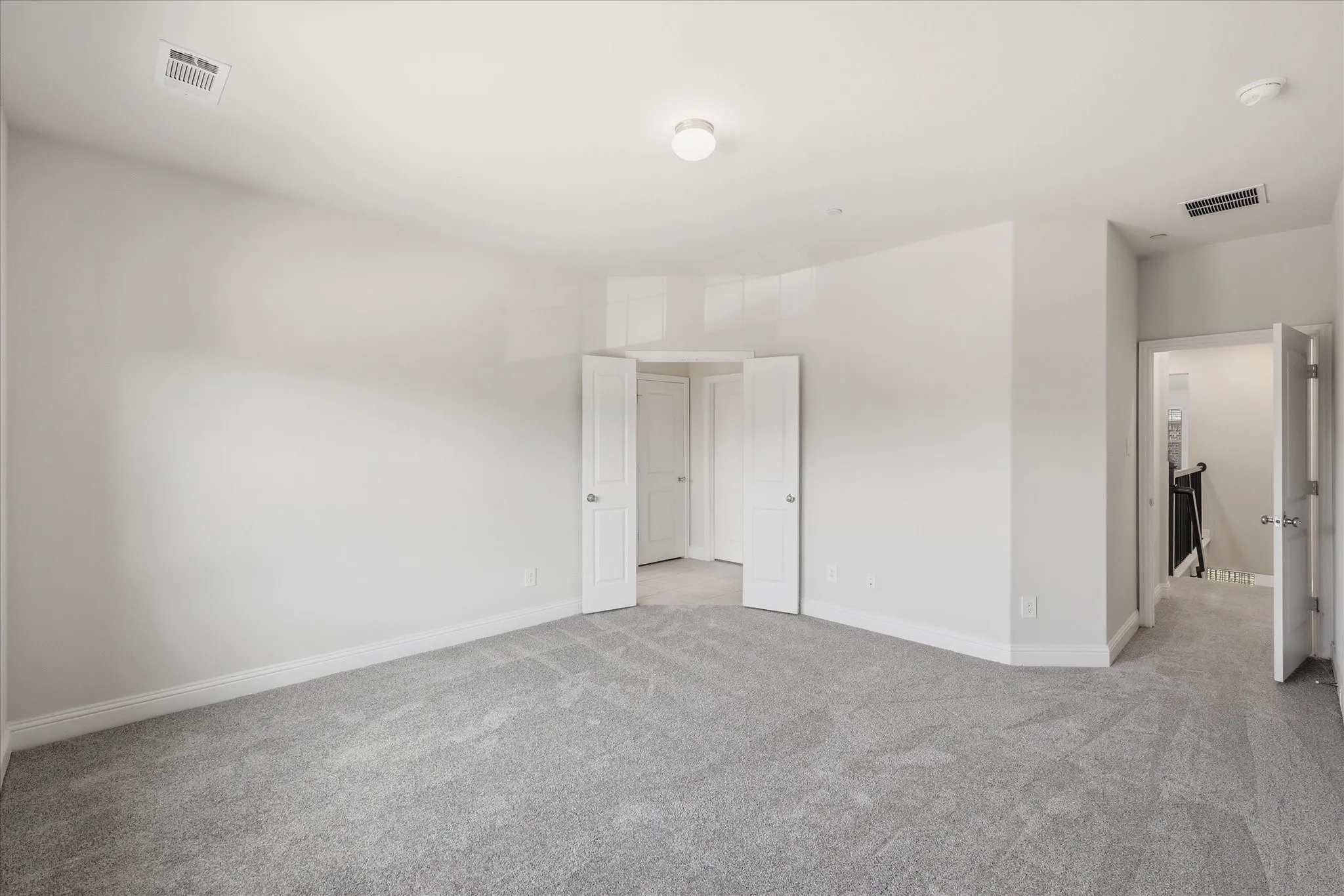 Spacious room with light gray carpeting, white walls, and a flush mount ceiling light