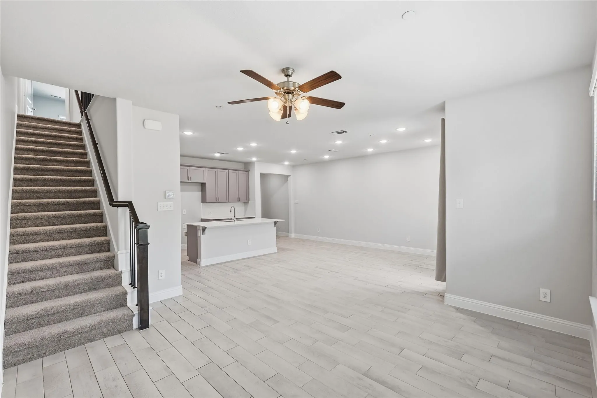 Open-concept living space featuring wood-finish tile flooring, recessed lighting, and a ceiling fan