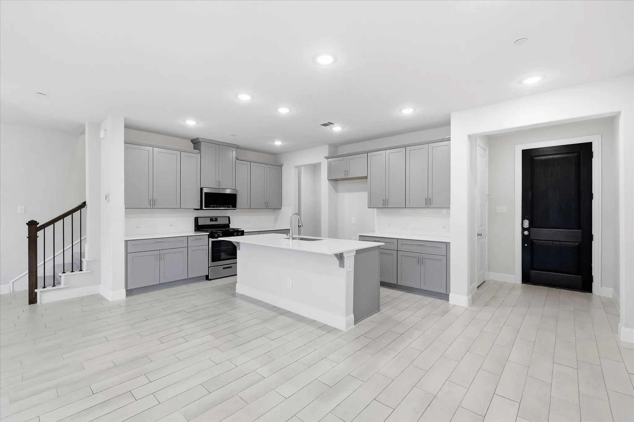 Contemporary kitchen featuring gray cabinetry, stainless steel appliances, a center island, and wood-finish flooring