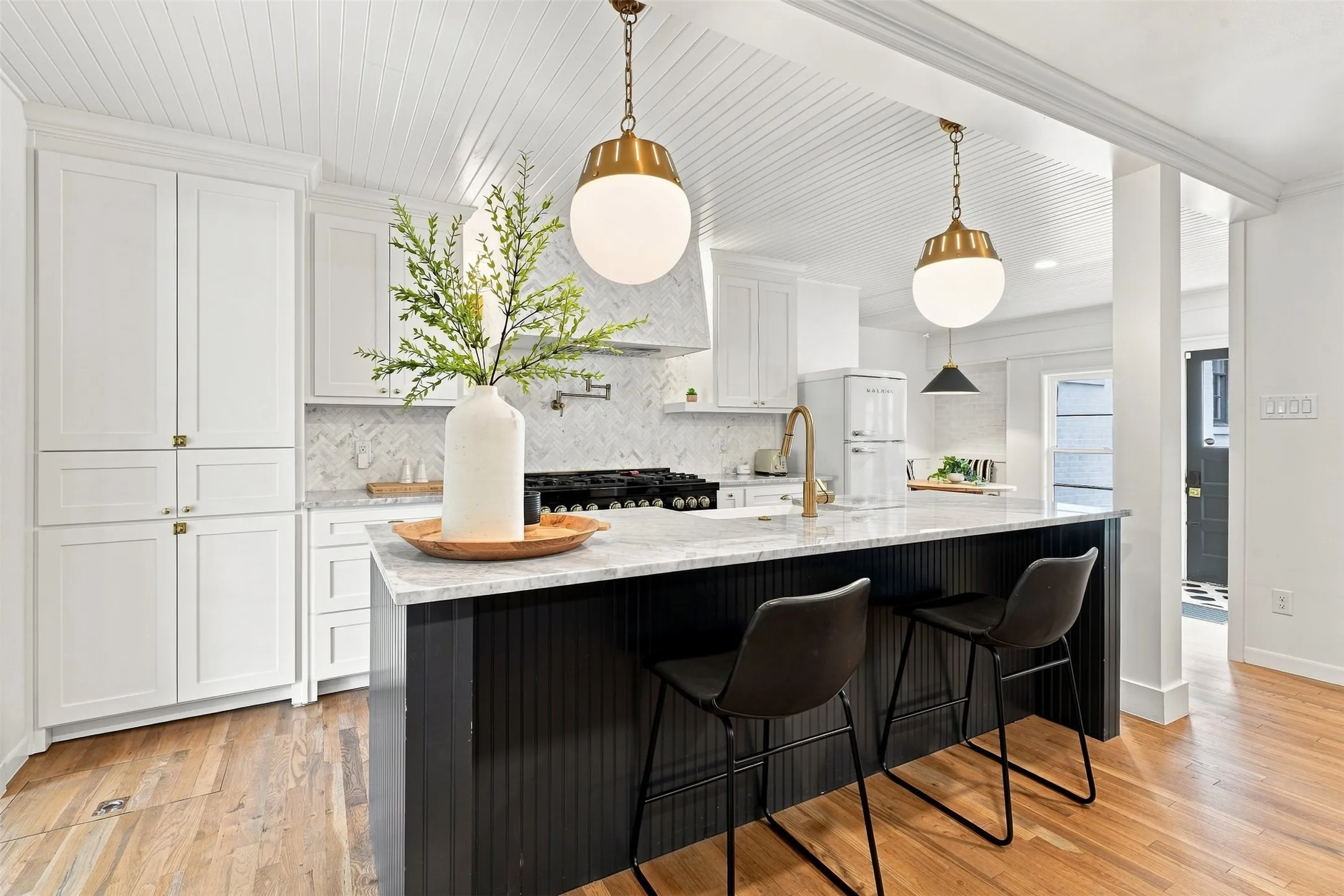 The showstopping kitchen is a masterful blend of timeless elegance and modern luxury, showcasing custom soft-close cabinetry and drawers, exquisite marble countertops, and thoughtfully selected designer lighting.