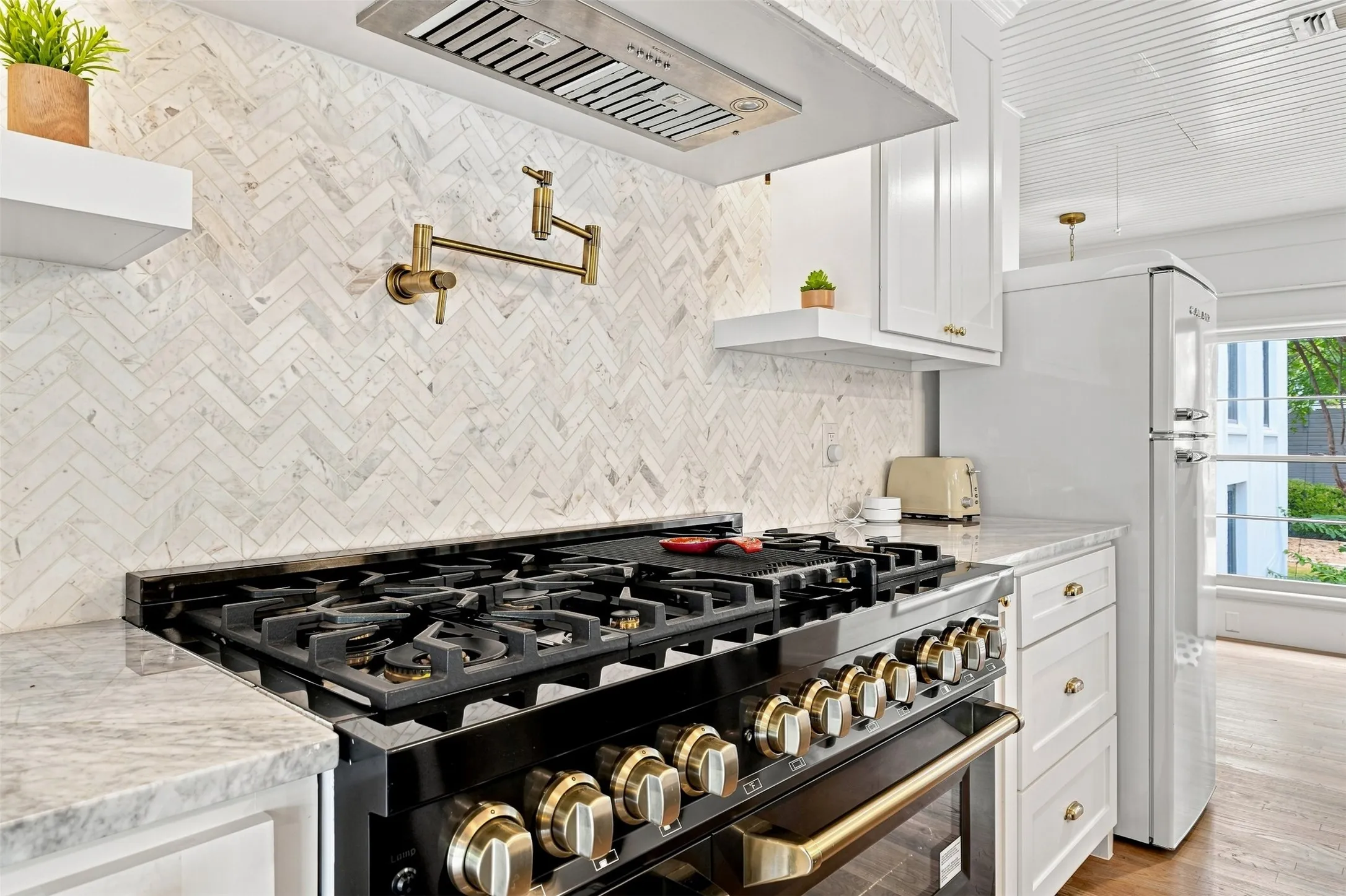 A commanding 48-inch professional-style gas range serves as the centerpiece, complemented by generous prep space and beautifully appointed finishes throughout.