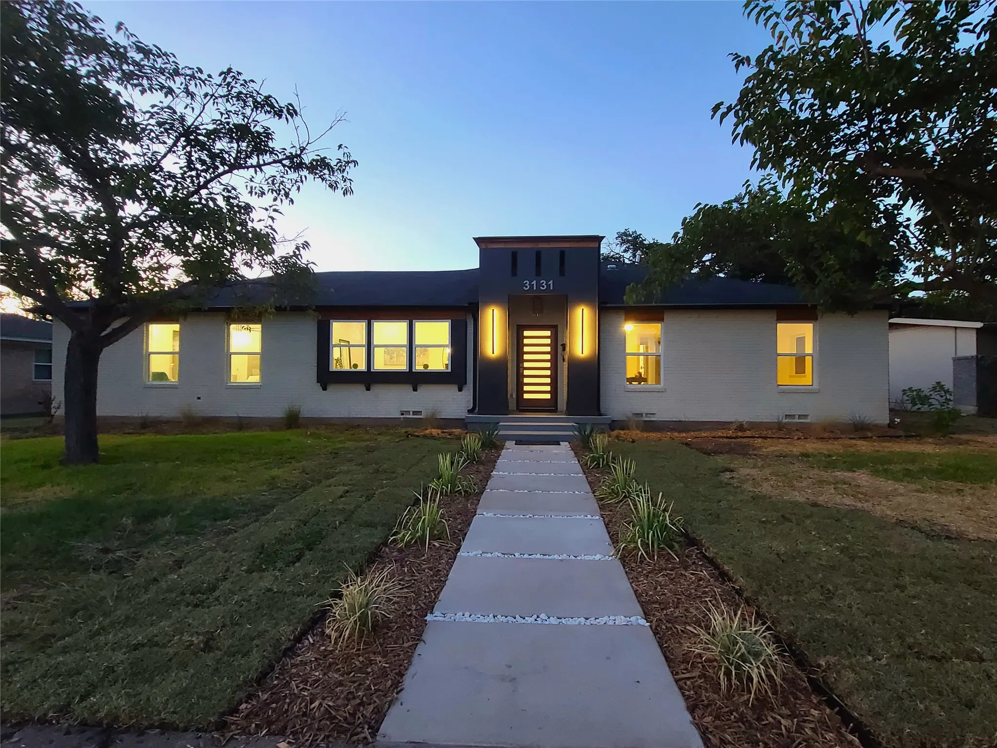 Modern exterior entry with vertical accent lighting, a wood-finish front door, and a dark accent facade