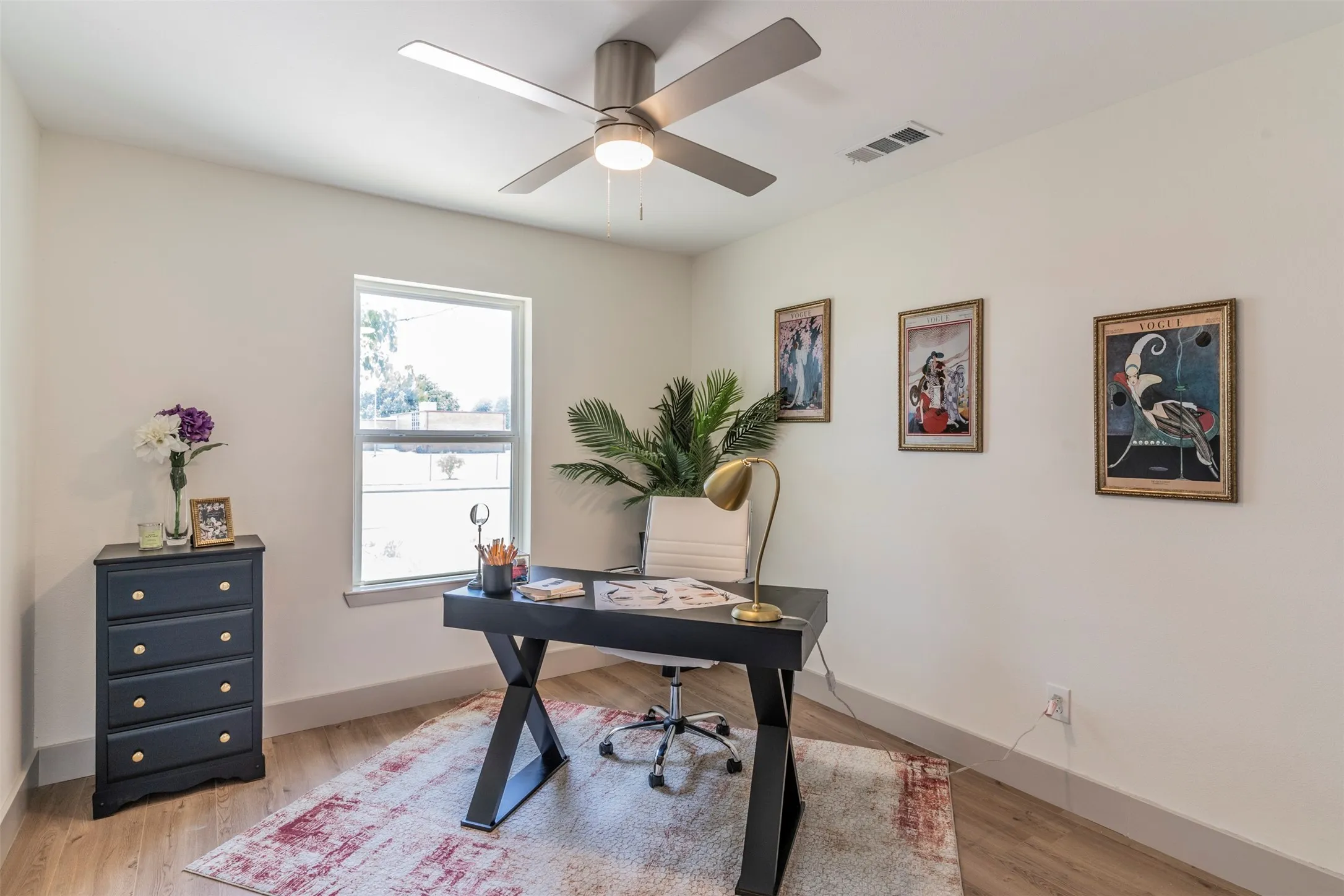 Neutral wall color, wood-finish flooring, ceiling fan with integrated lighting, single-pane window, and light-toned trim