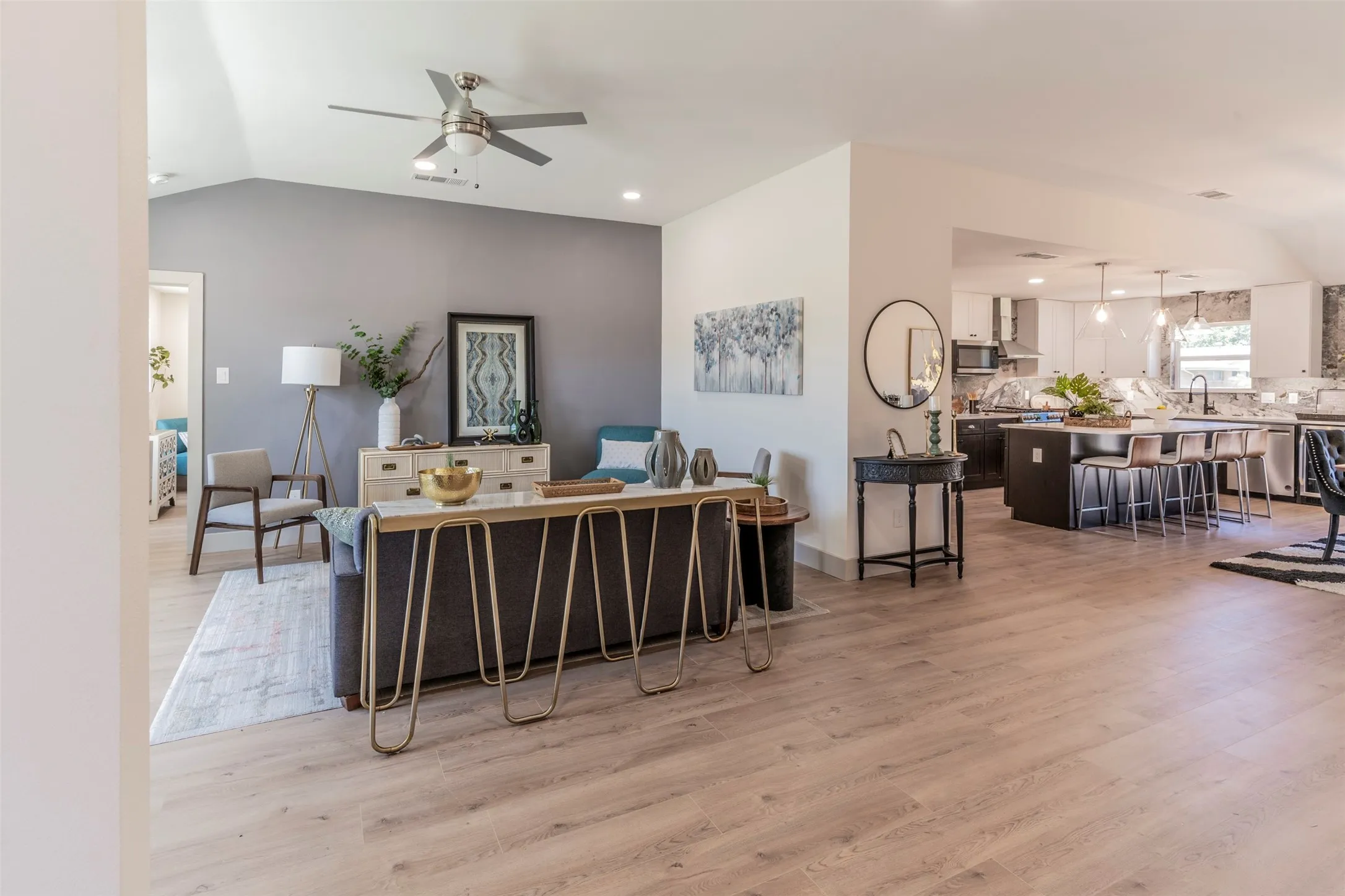 Open-concept living area with vaulted ceilings, wood-finish flooring, and a ceiling fan