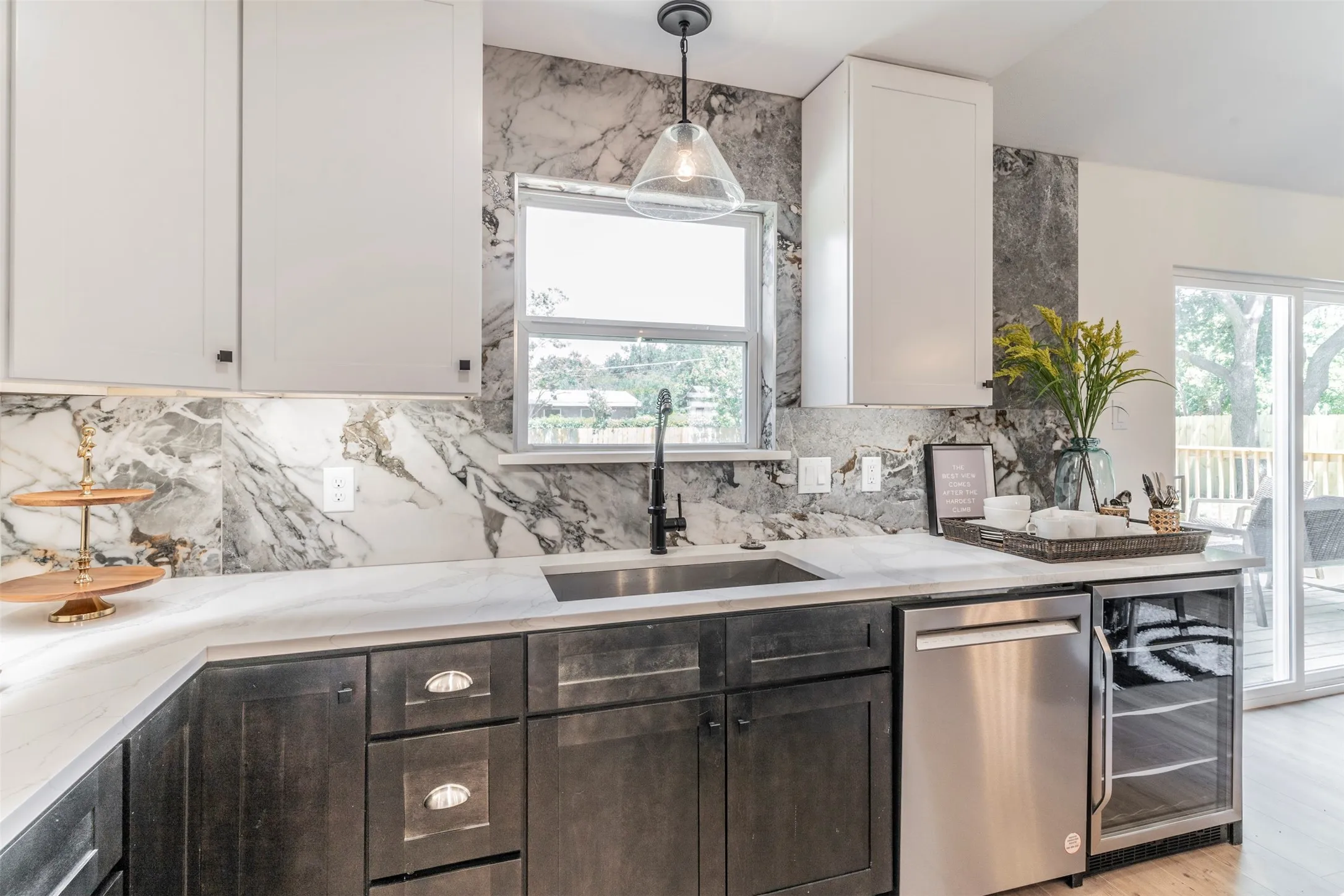 Kitchen featuring white upper cabinetry, dark wood-finish lower cabinetry, a stainless steel sink, and a stainless steel dishwasher