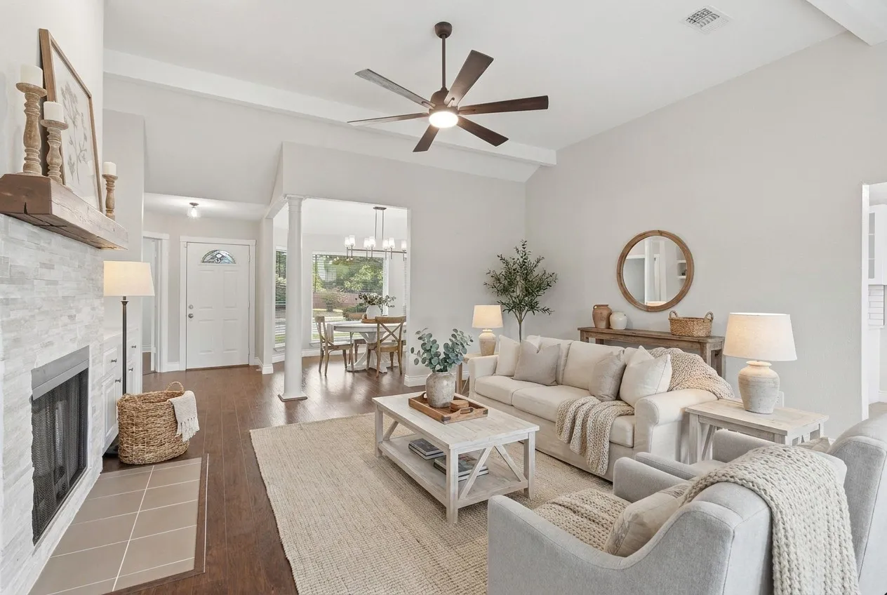 Virtually staged. Living room with new ceiling fan, wood burning fireplace and built-in storage area with quartz countertops.