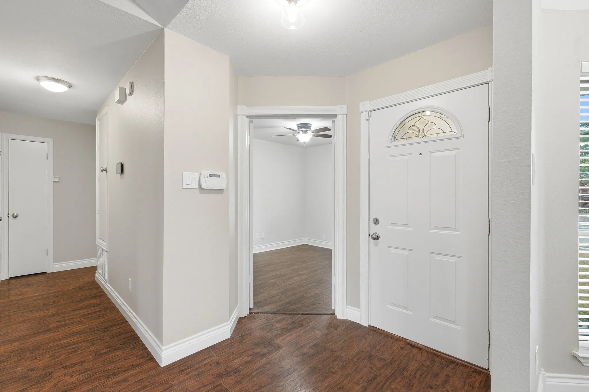 Entry area with double doors to secondary bedroom with ceiling fan and closet.