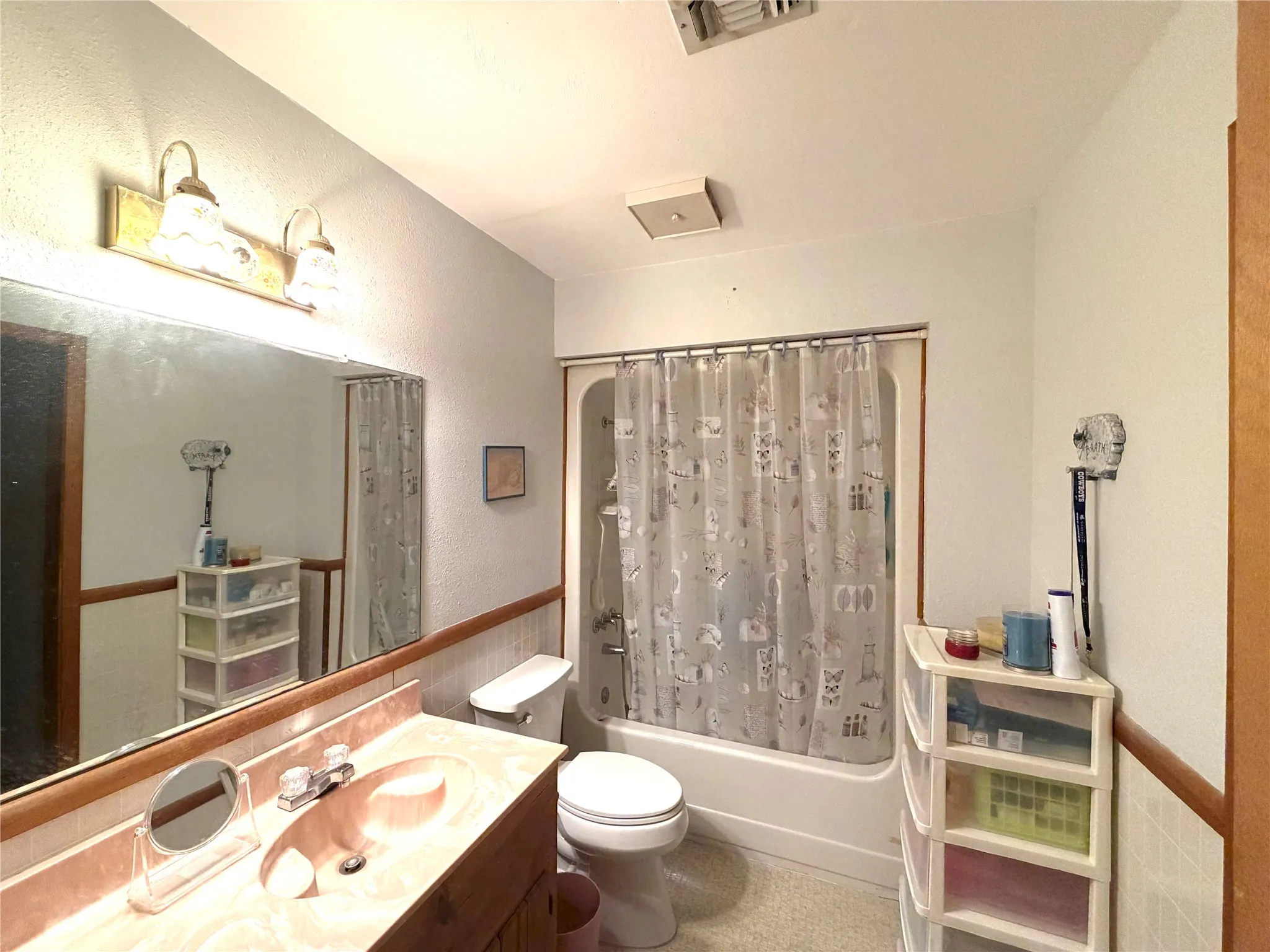 Wall-mounted vanity light fixture above a large wall mirror