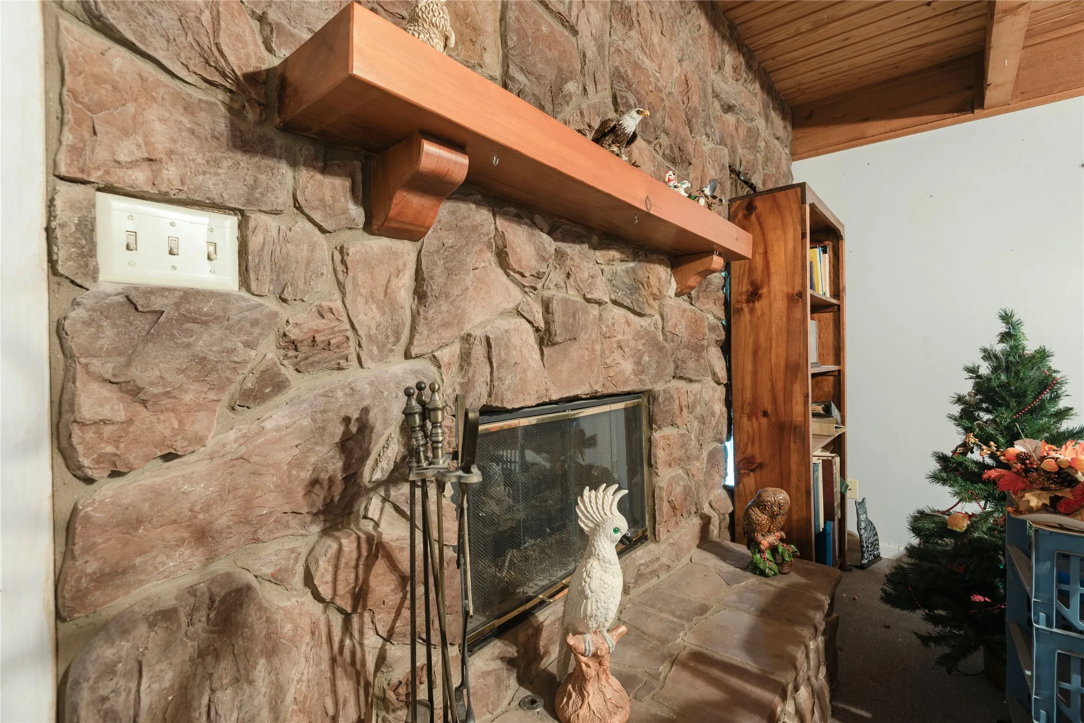 Stone fireplace with a wood mantel, integrated fire screen, and a hearth