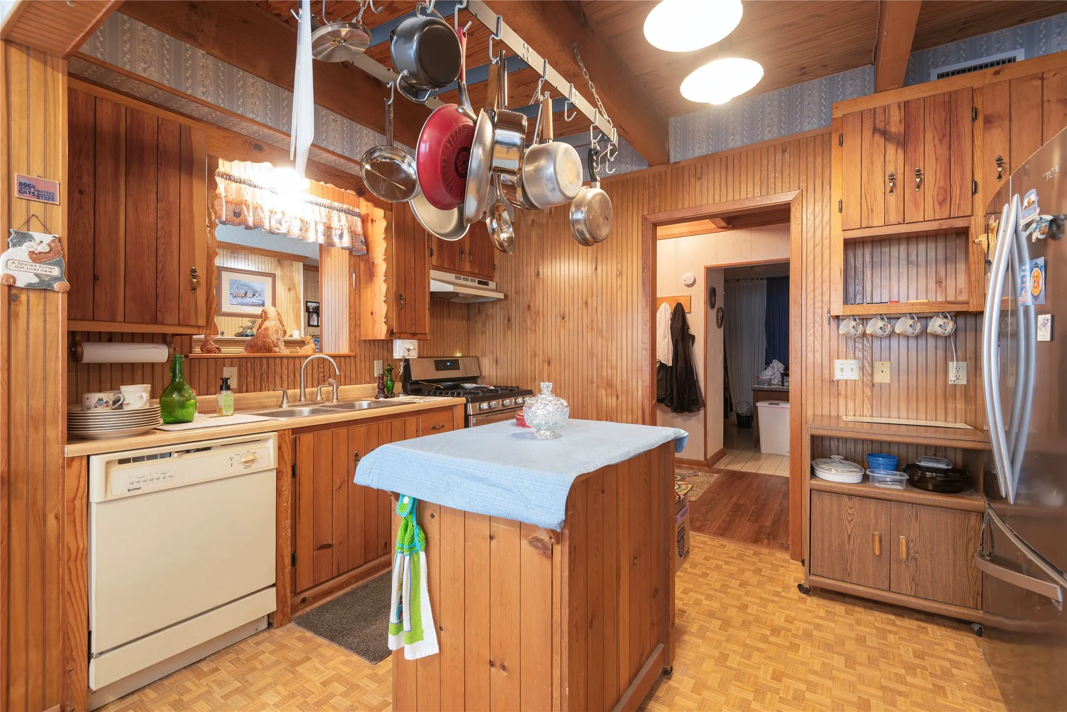 Kitchen featuring wood paneling, wood-finish cabinetry, stainless steel refrigerator, and recessed lighting