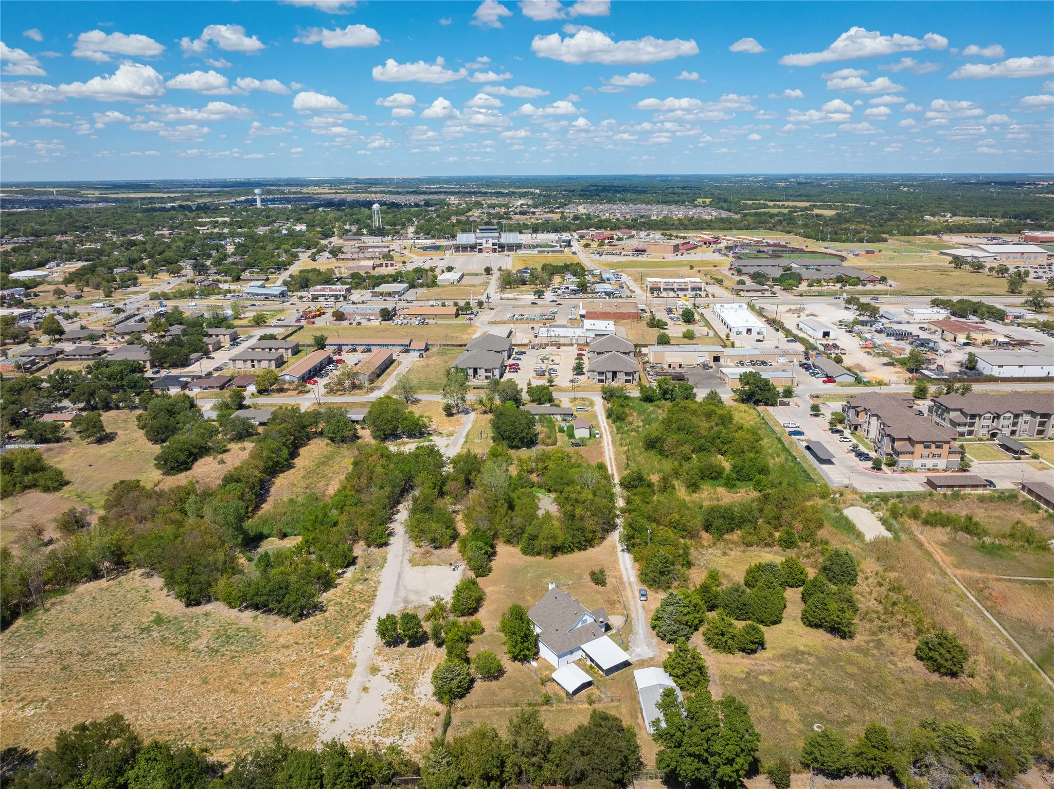 Expansive land parcel with surrounding development and distant commercial structures