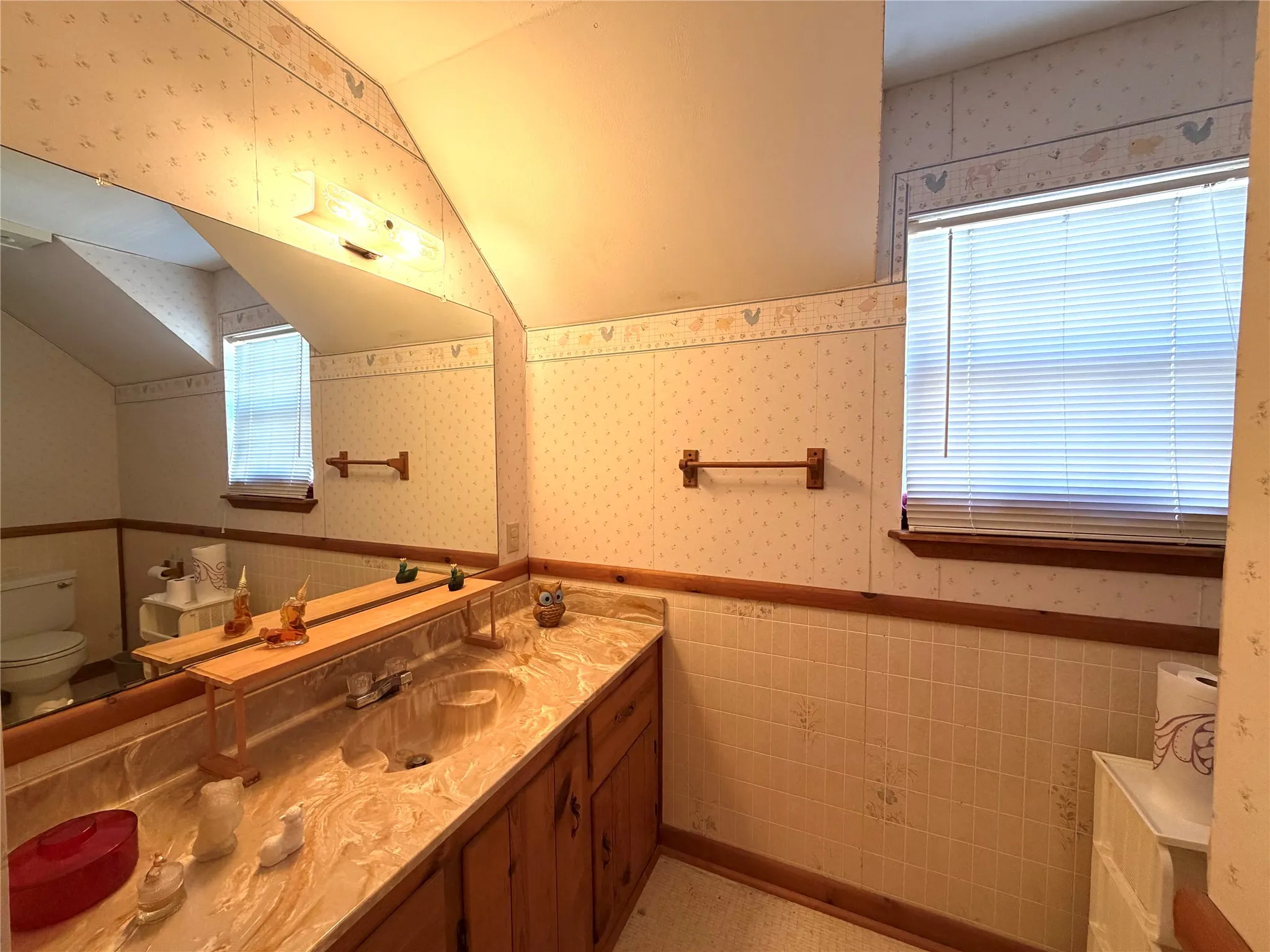 Dual vanity with integrated sinks, expansive mirror, vanity lighting, and natural wood cabinetry