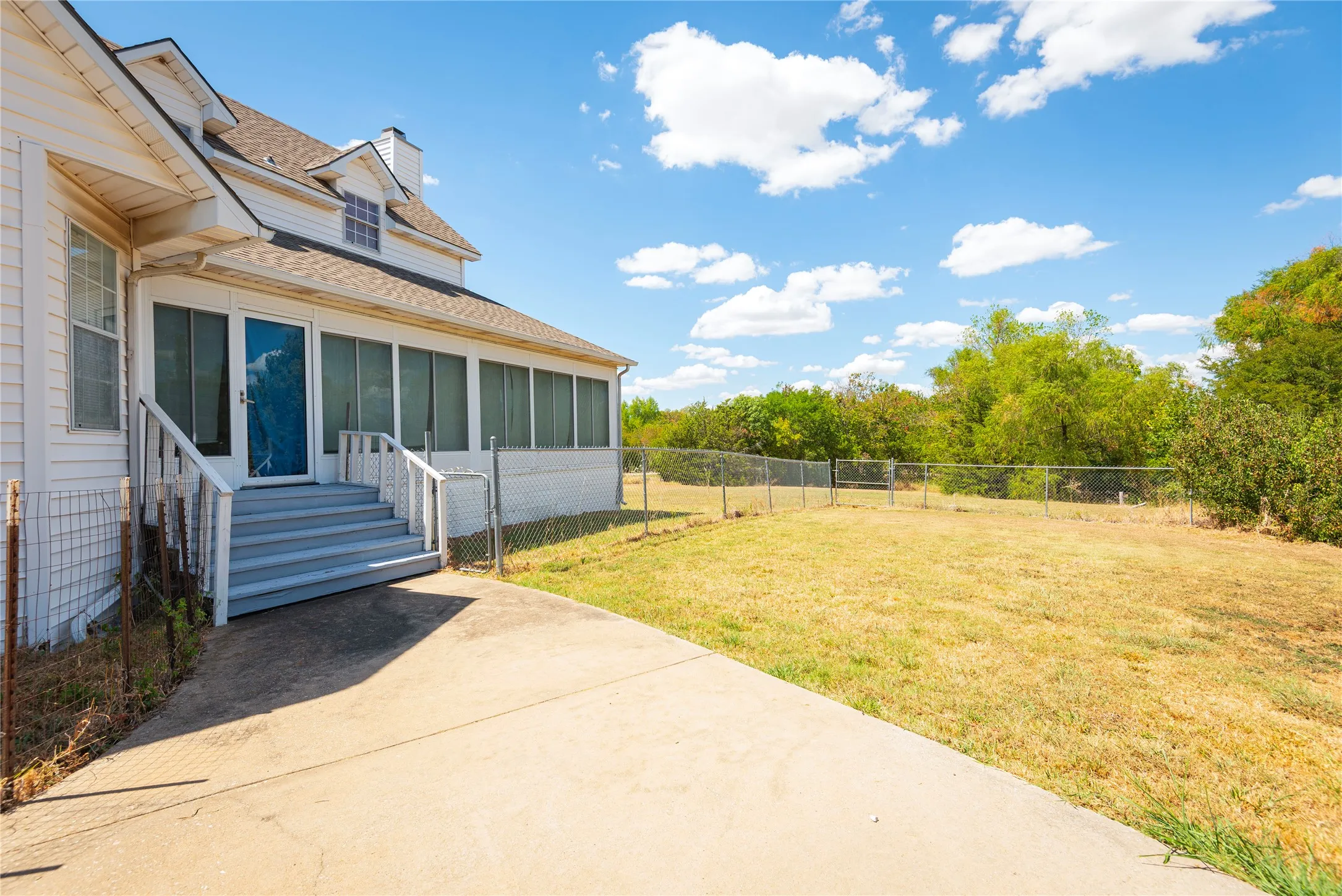 White siding exterior with a screened porch, dormer windows, and a fenced yard