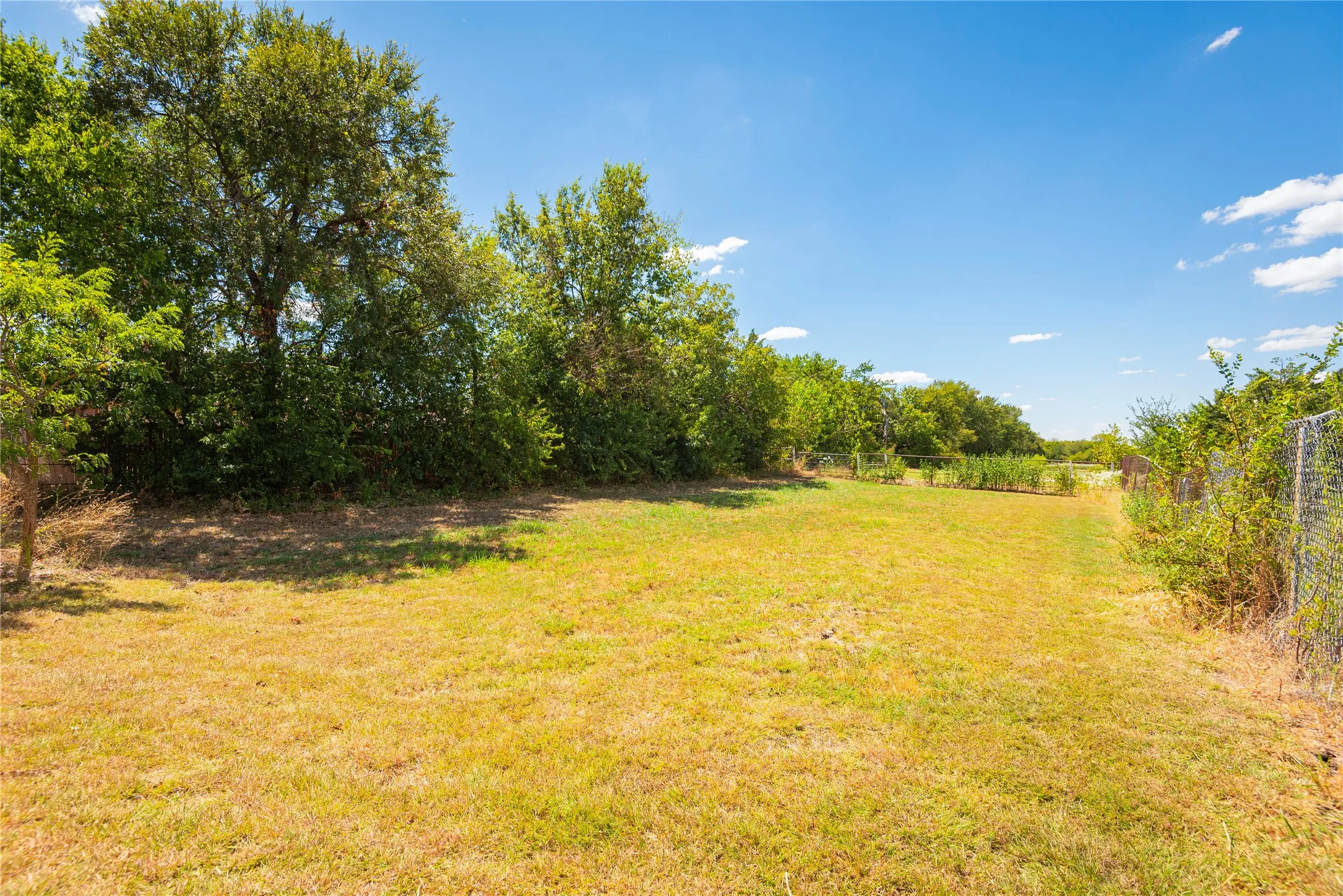 Expansive outdoor area with natural landscaping and a partially fenced perimeter