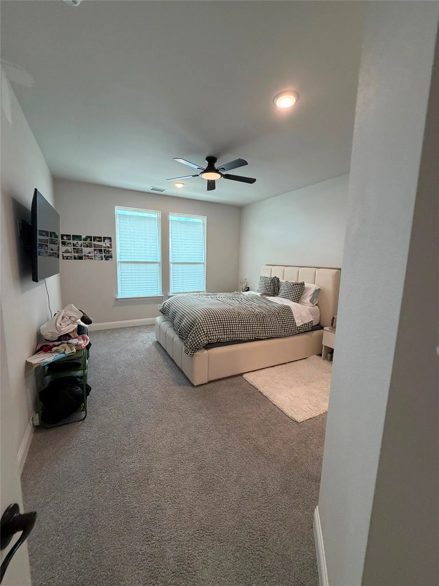 Recessed lighting, ceiling fan with integrated light, two windows with blinds, and gray carpeting