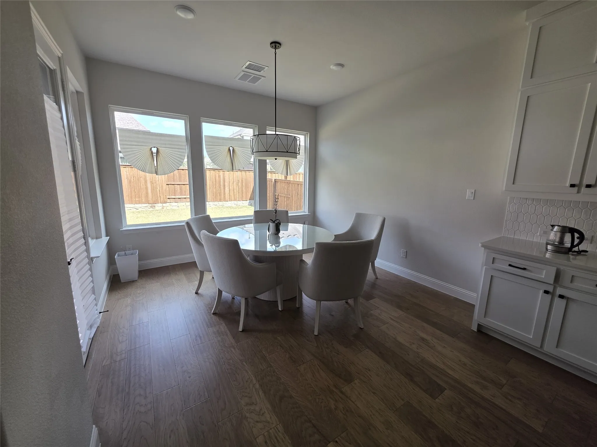 Wood-finish flooring, white shaker-style cabinetry, patterned tile backsplash, recessed lighting, and a contemporary chandelier