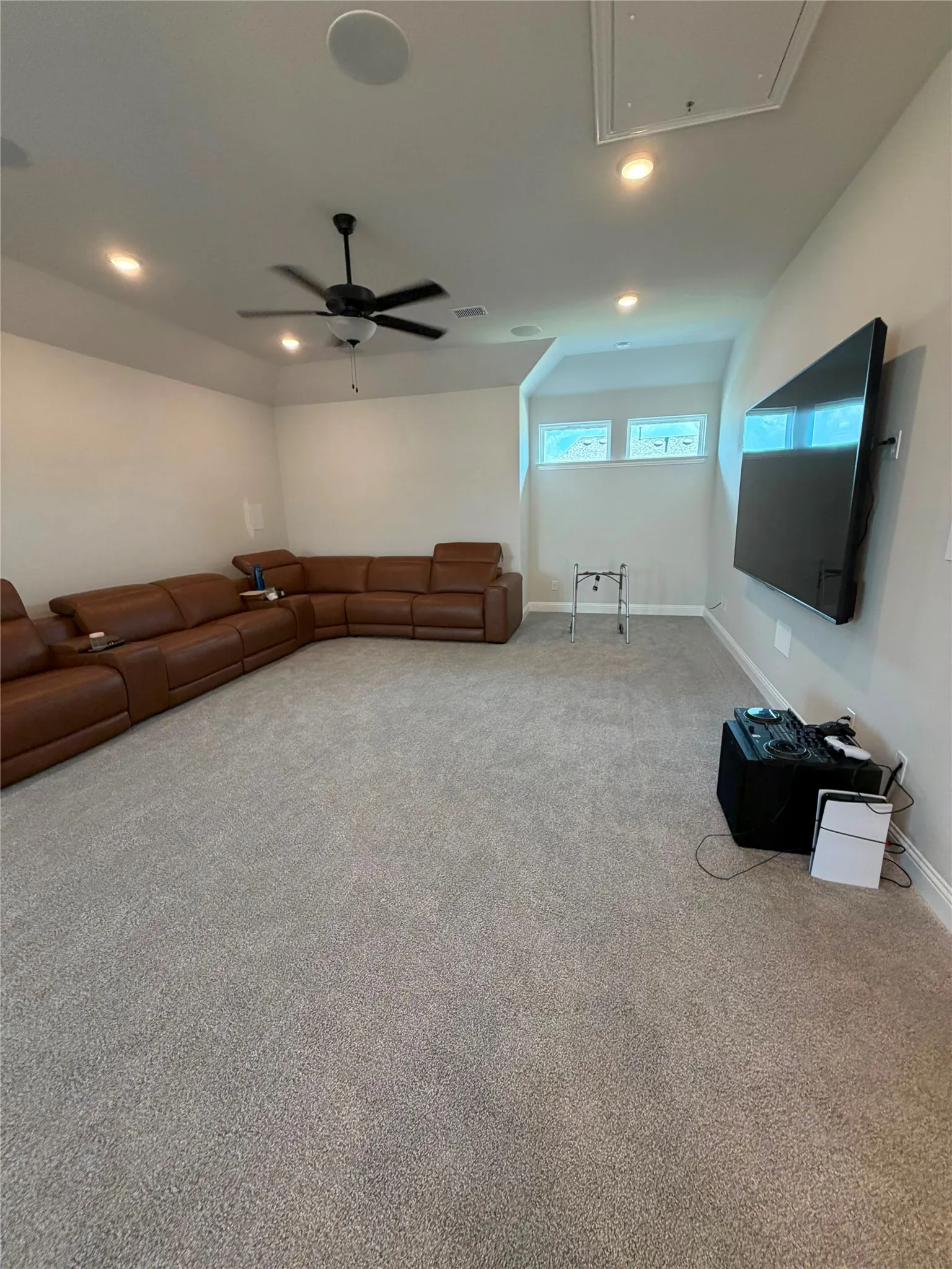 Recessed lighting, ceiling fan, wall-mounted television, and carpet flooring