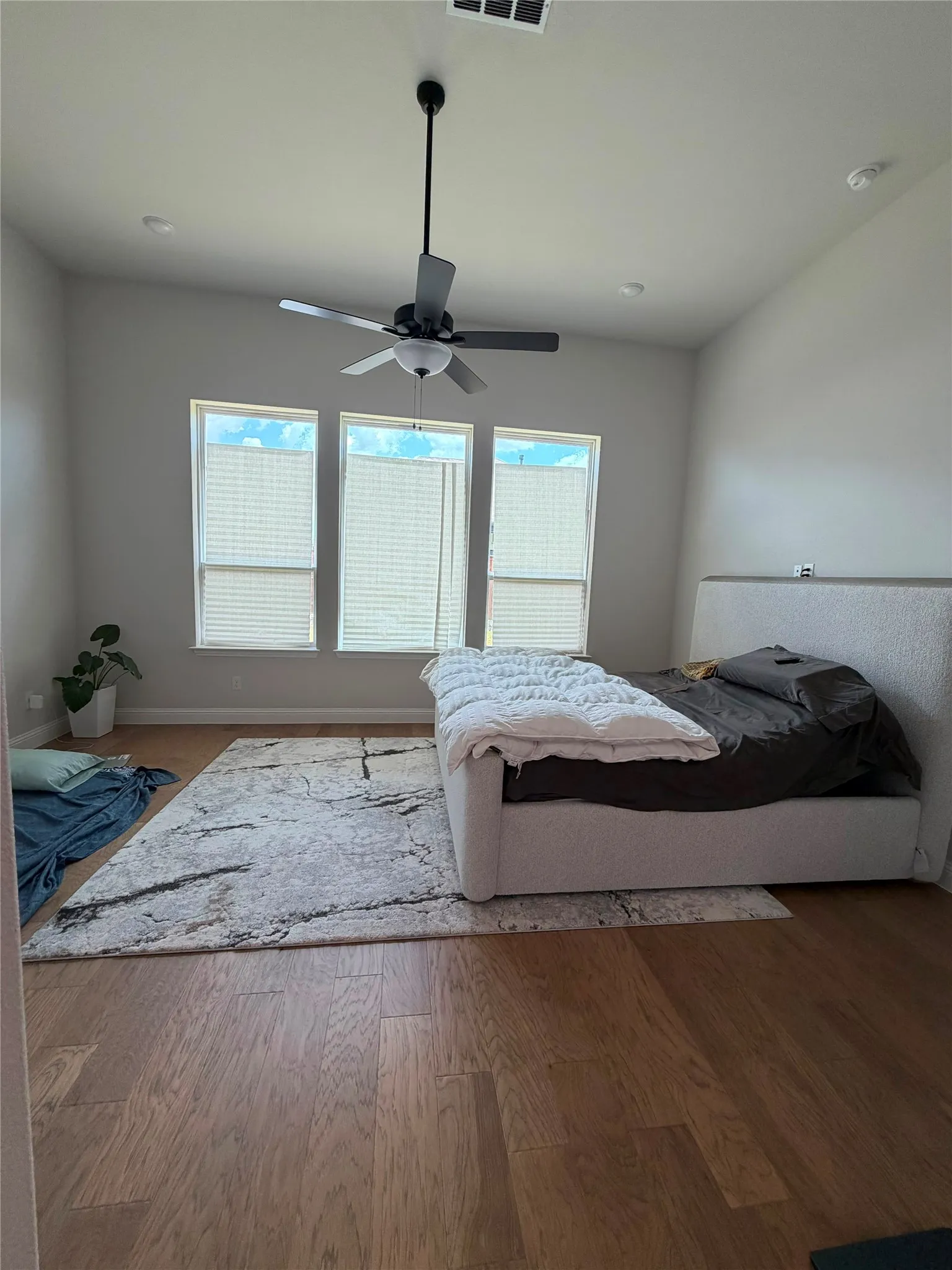 Wood-finish flooring, high ceilings with a modern ceiling fan, recessed lighting, and multiple windows with blinds