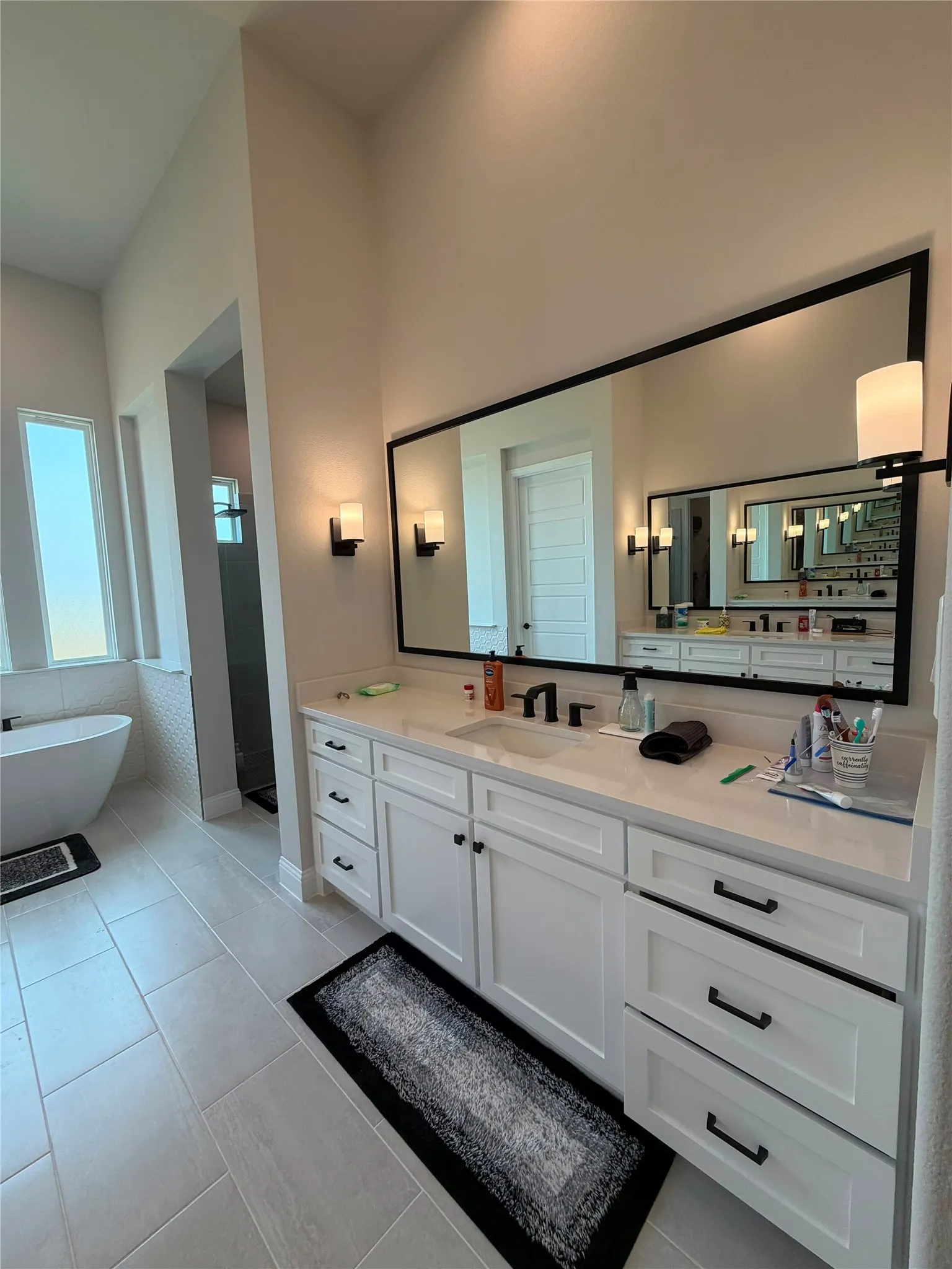 White double vanity with integrated sinks, black hardware, and a large framed mirror