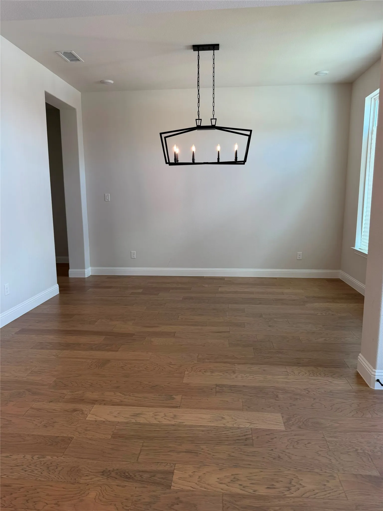 Wood-finish flooring, contemporary chandelier, recessed ceiling light, white baseboards, and window with blinds