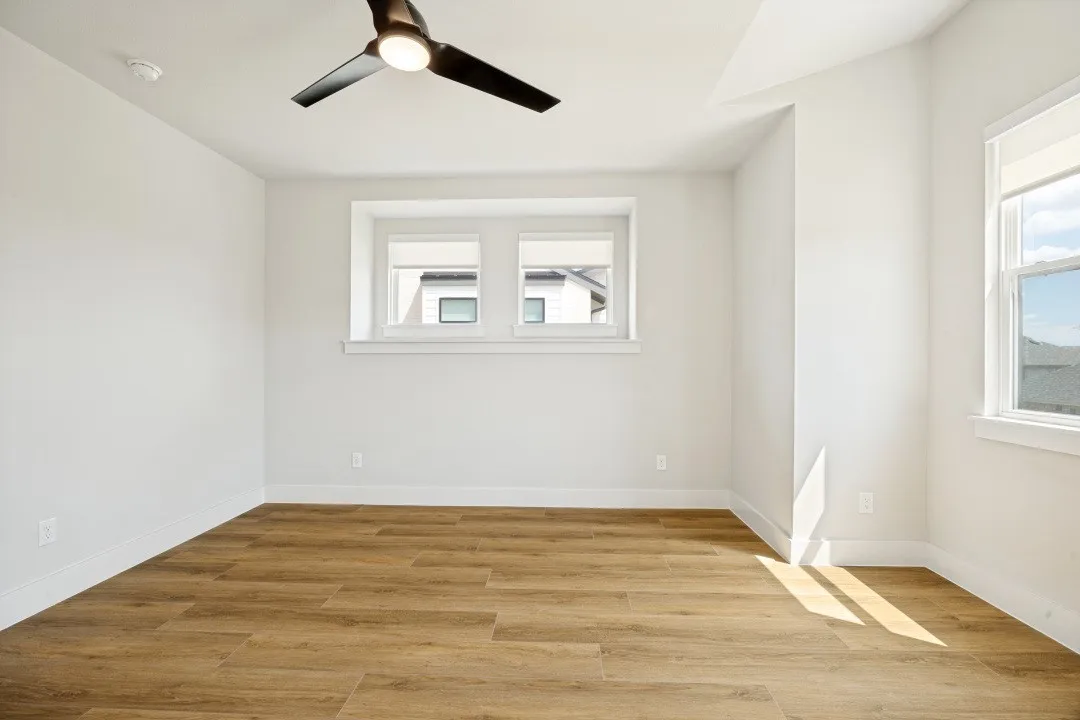 Expansive interior featuring wood-finish flooring, multiple windows, a ceiling fan, and white baseboards