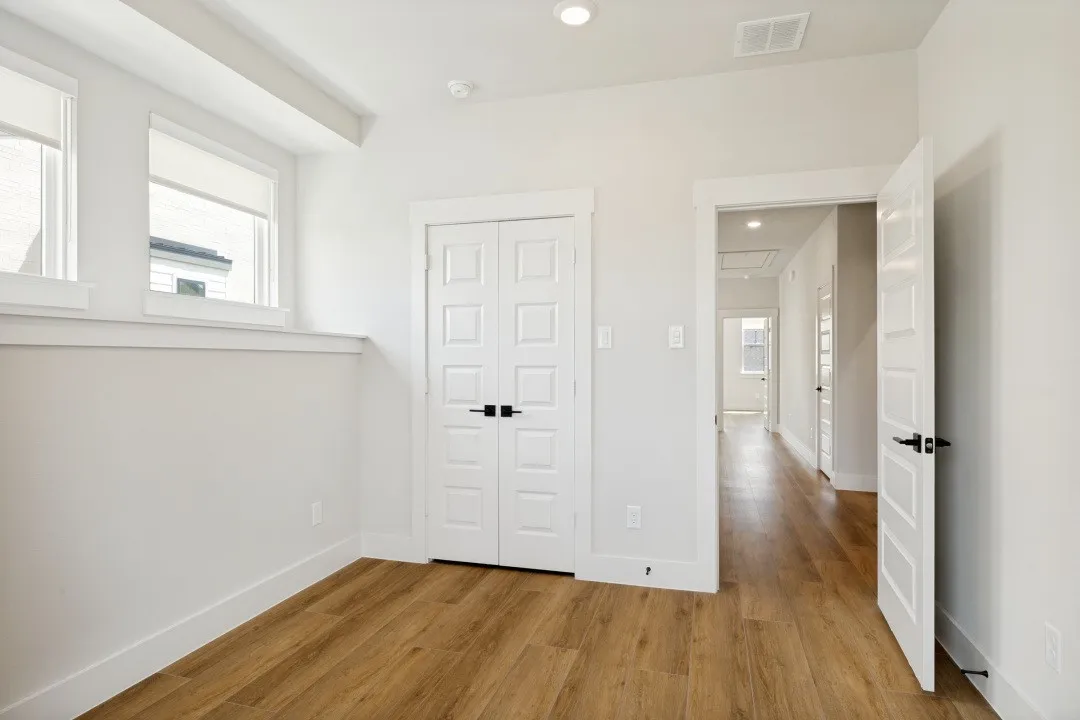 Wood-finish flooring throughout, white paneled doors with black hardware, and recessed lighting