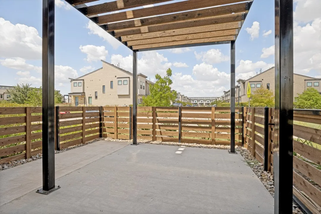 Private patio with concrete flooring, accented by river rock landscaping, and enclosed by a horizontal slat wood fence
