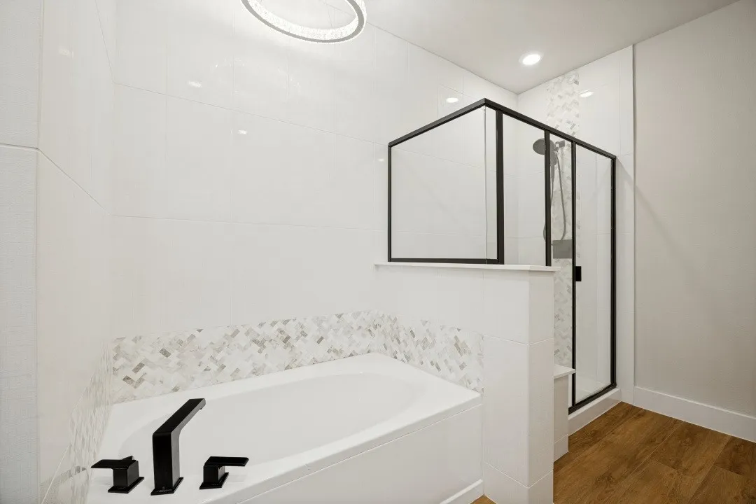 Soaking tub with matte black fixtures, white tile surround, and mosaic accent tile  Stand alone over sized shower