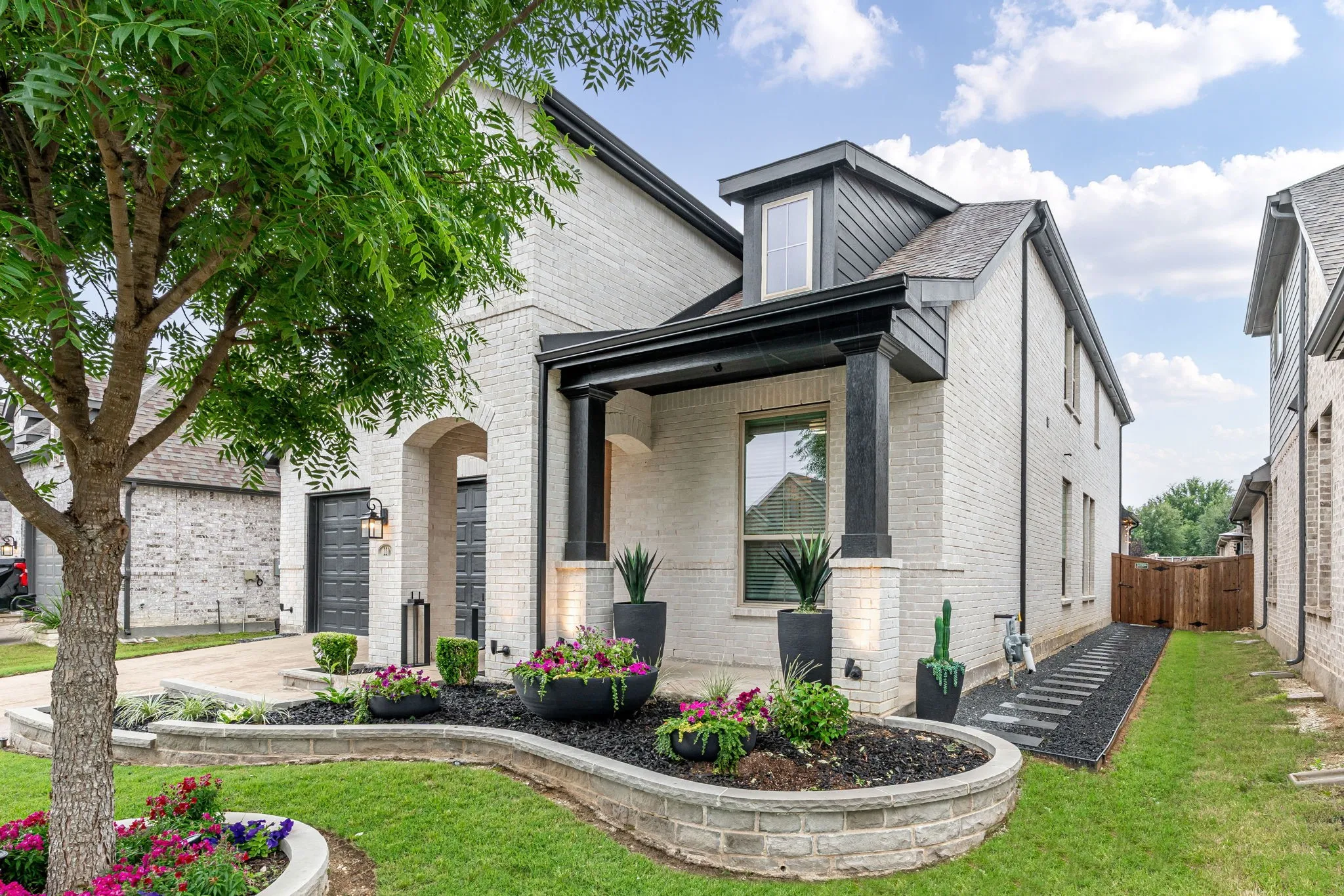 Note the hardscaped walkway with pavers to easily access backyard & the stone enhanced flowerbeds.