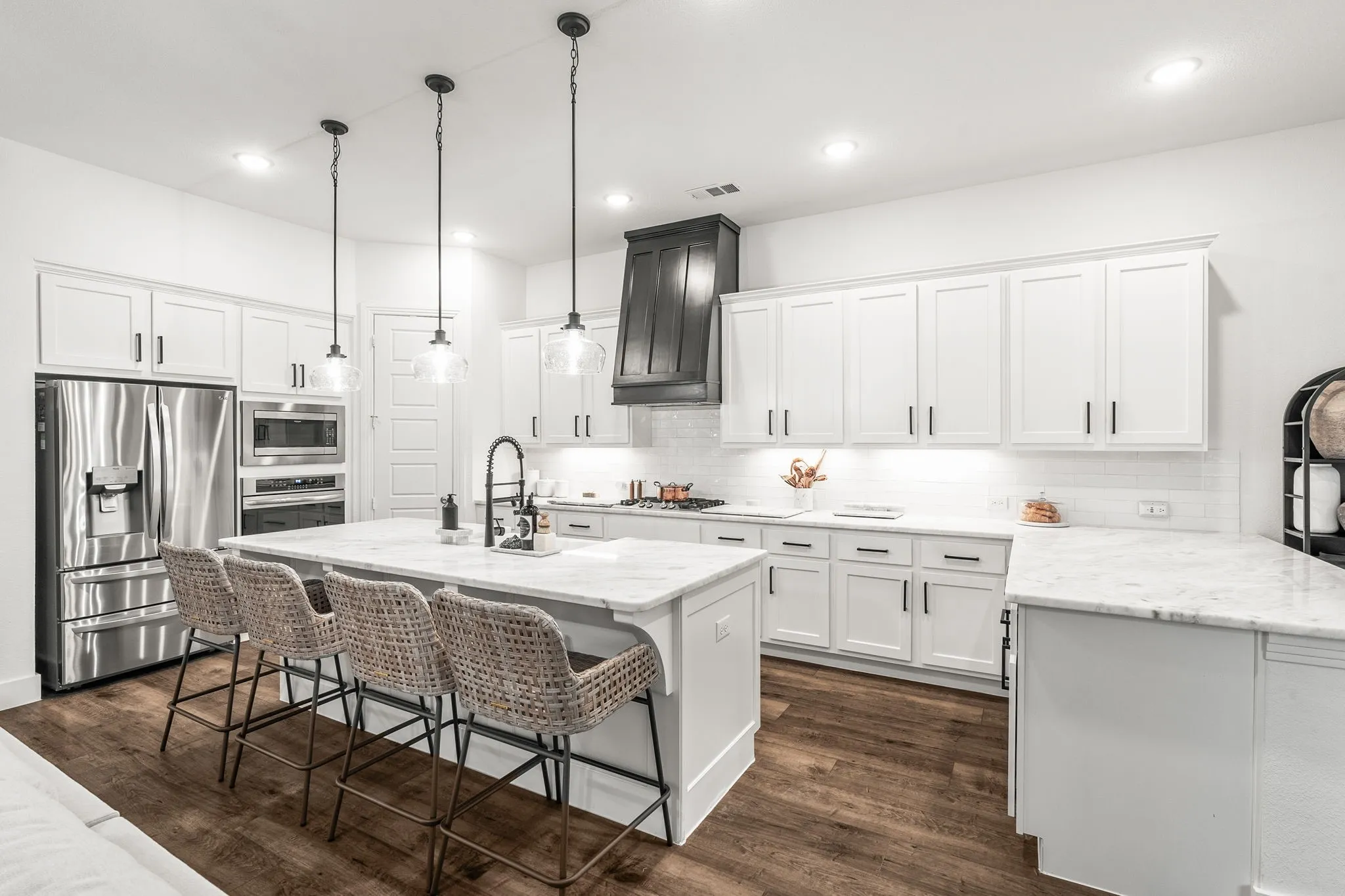 Quartz countertops, stainless steel appliances, a premium 4-burner gas cooktop, stacked microwave & oven, an oversized island offering abundant prep space and additional eating area, custom range hood, upgraded faucet, & designer cabinet hardware making it a true culinary dream.