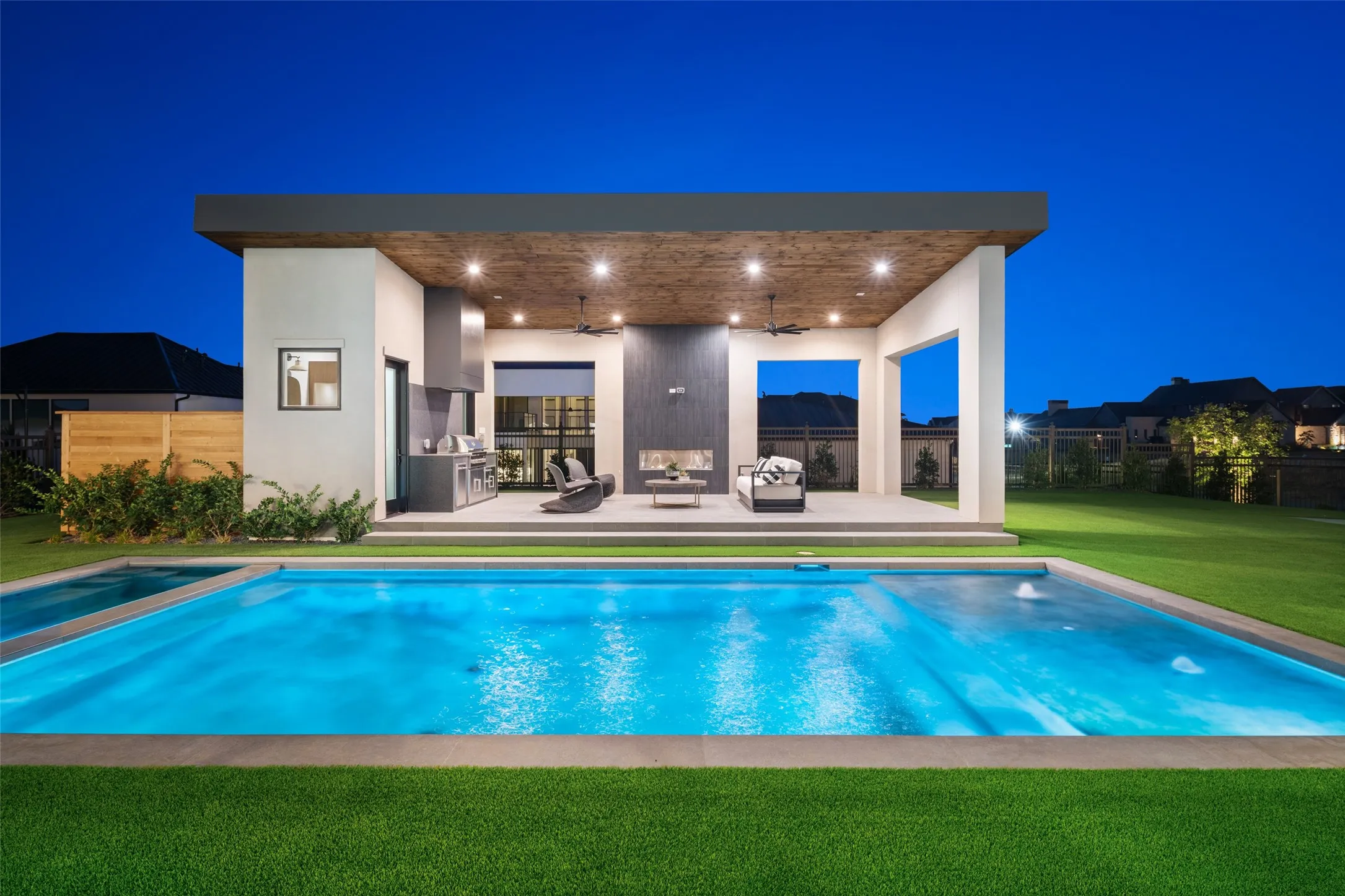 Outdoor living area with a built-in kitchen, fireplace, and flat-screen television