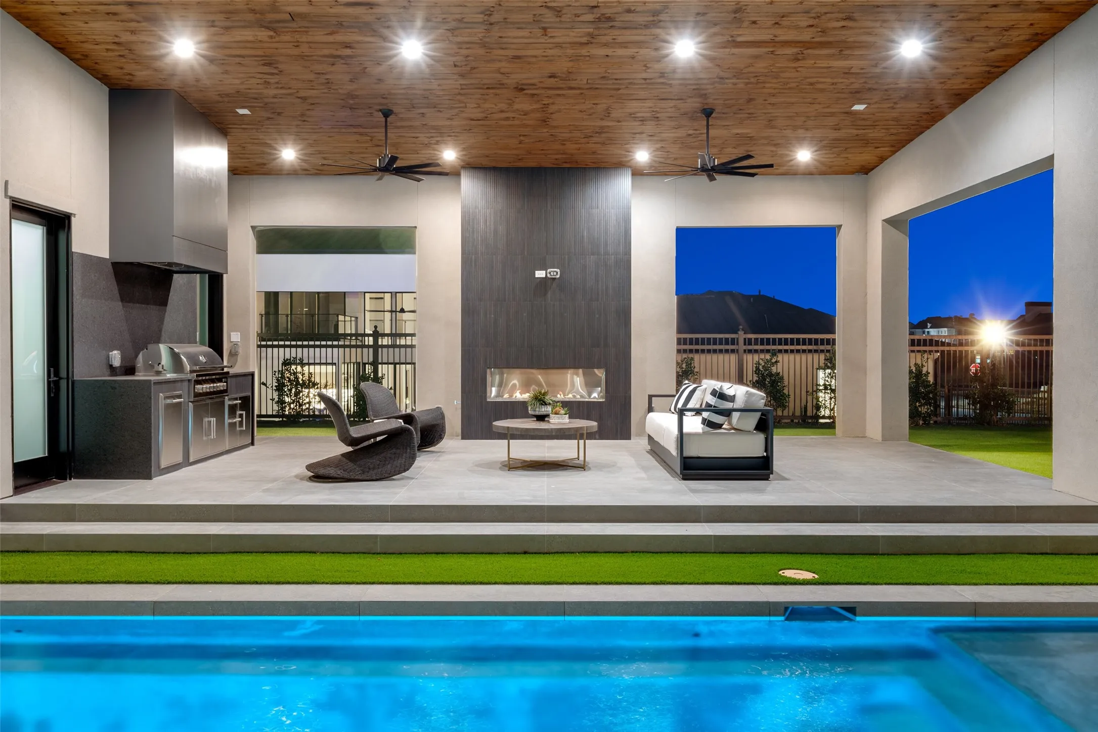 Covered patio with wood-finish ceiling, built-in outdoor kitchen, linear fireplace, recessed lighting, and ceiling fans