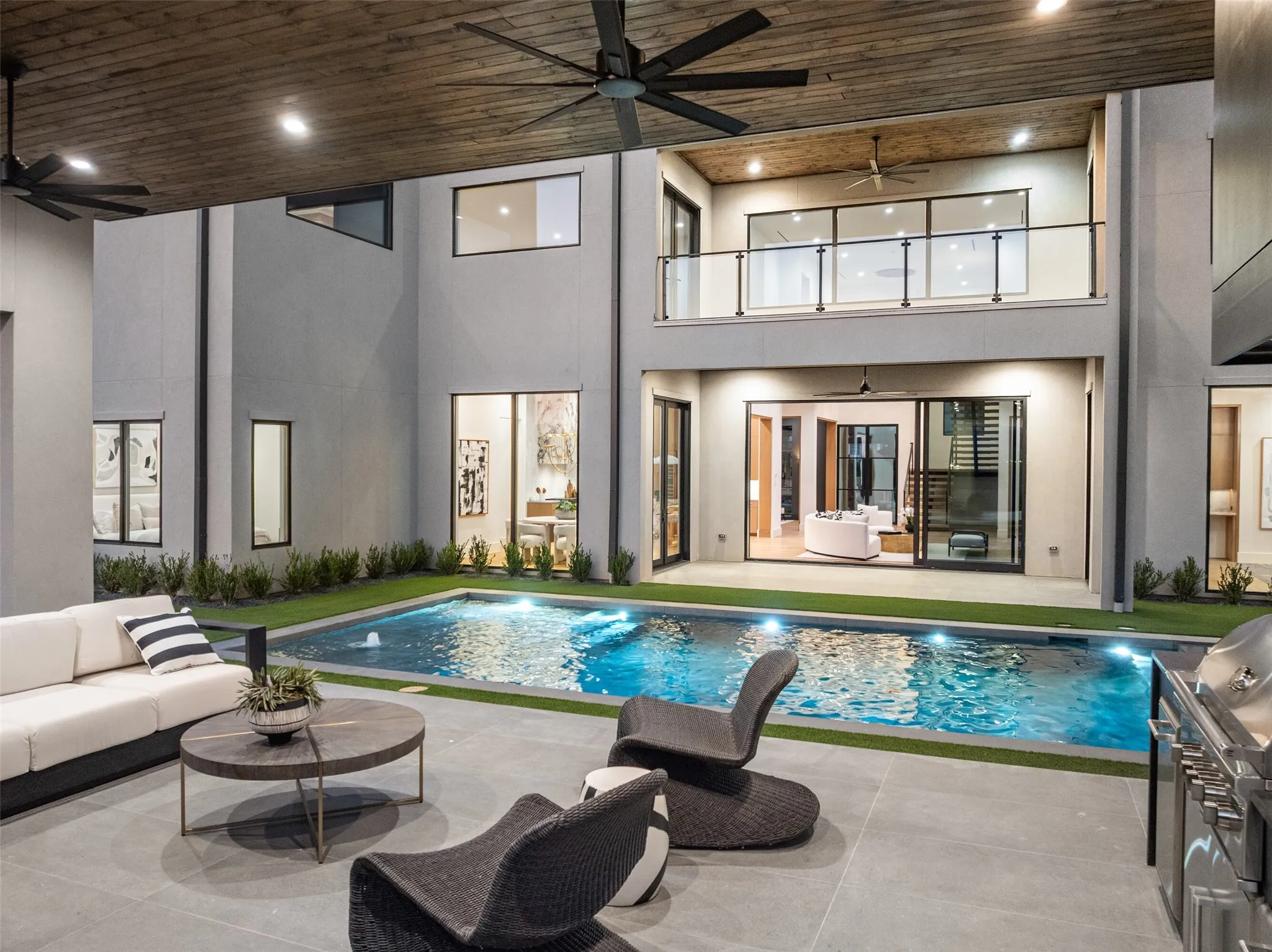 Outdoor patio with a built-in grill, an in-ground swimming pool, and a second-story balcony with glass railings