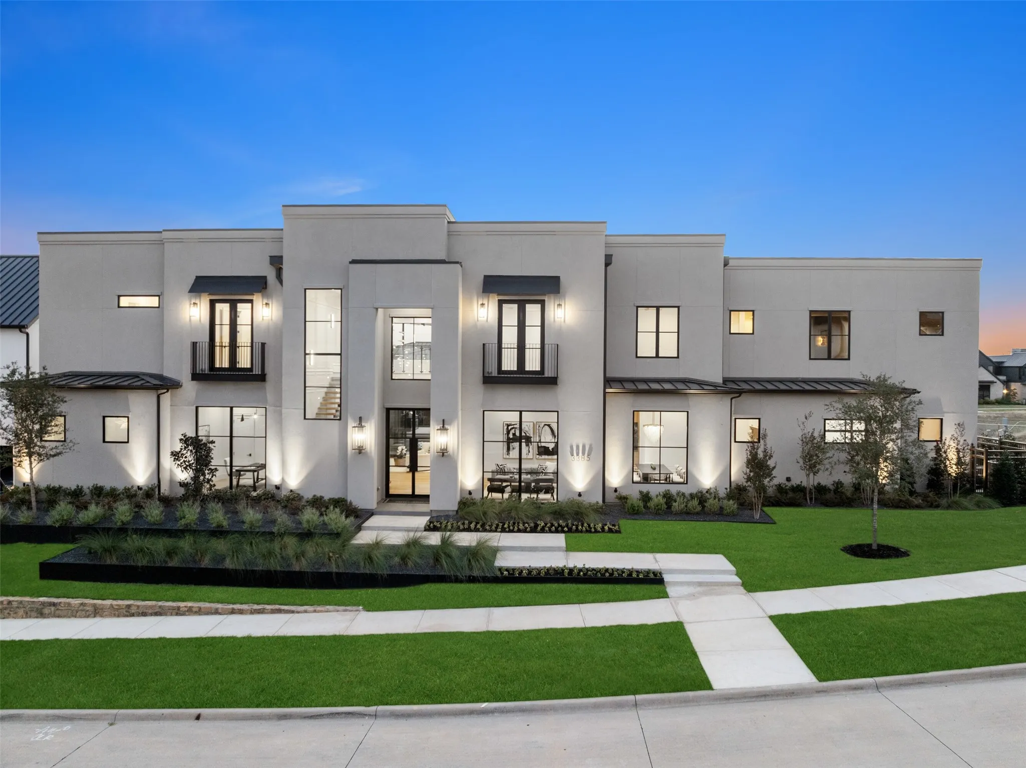 Contemporary stucco exterior with prominent architectural lines, multiple large windows, and a well-maintained lawn