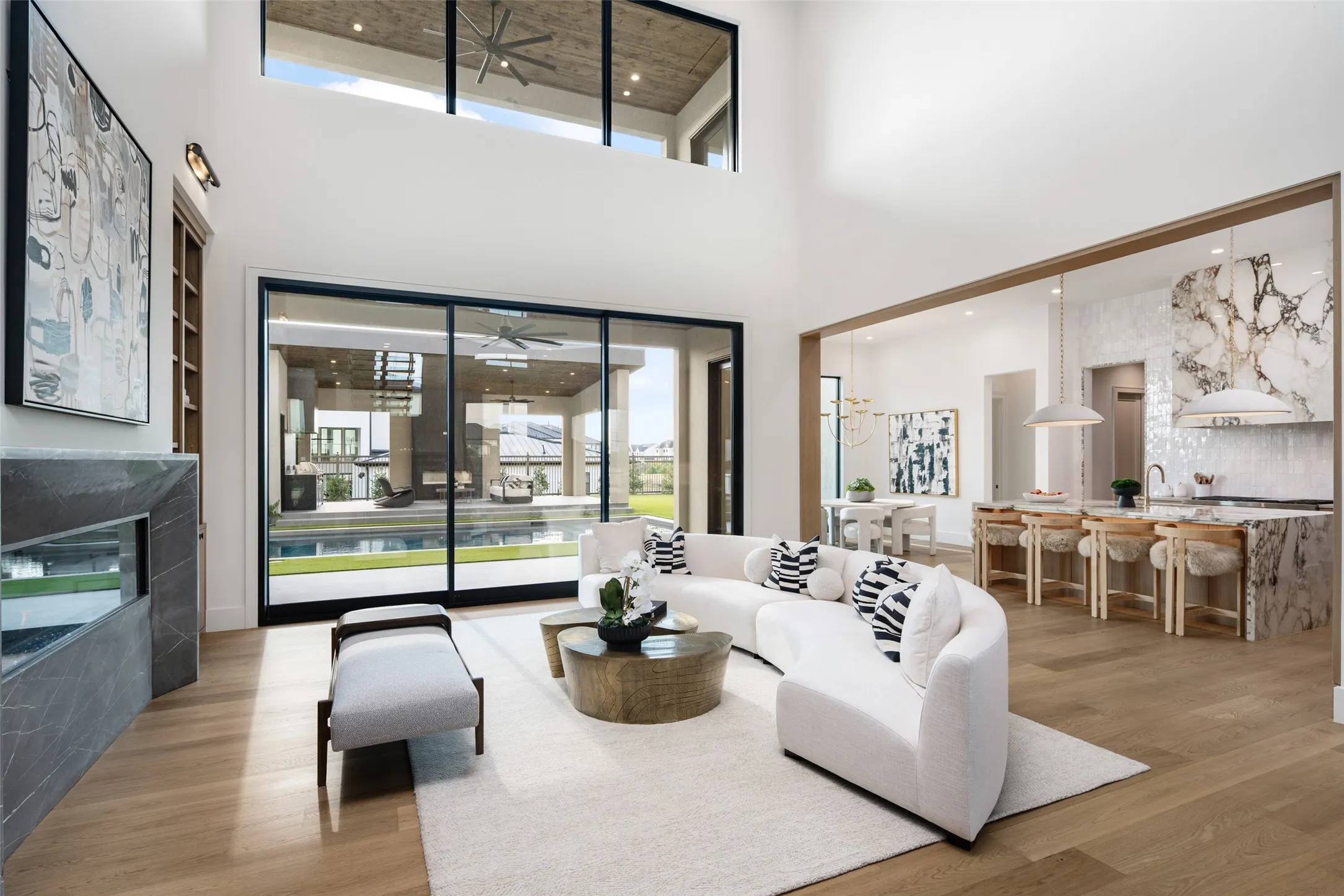 Two-story living area with high ceilings, featuring wood-finish flooring and a fireplace with a stone surround