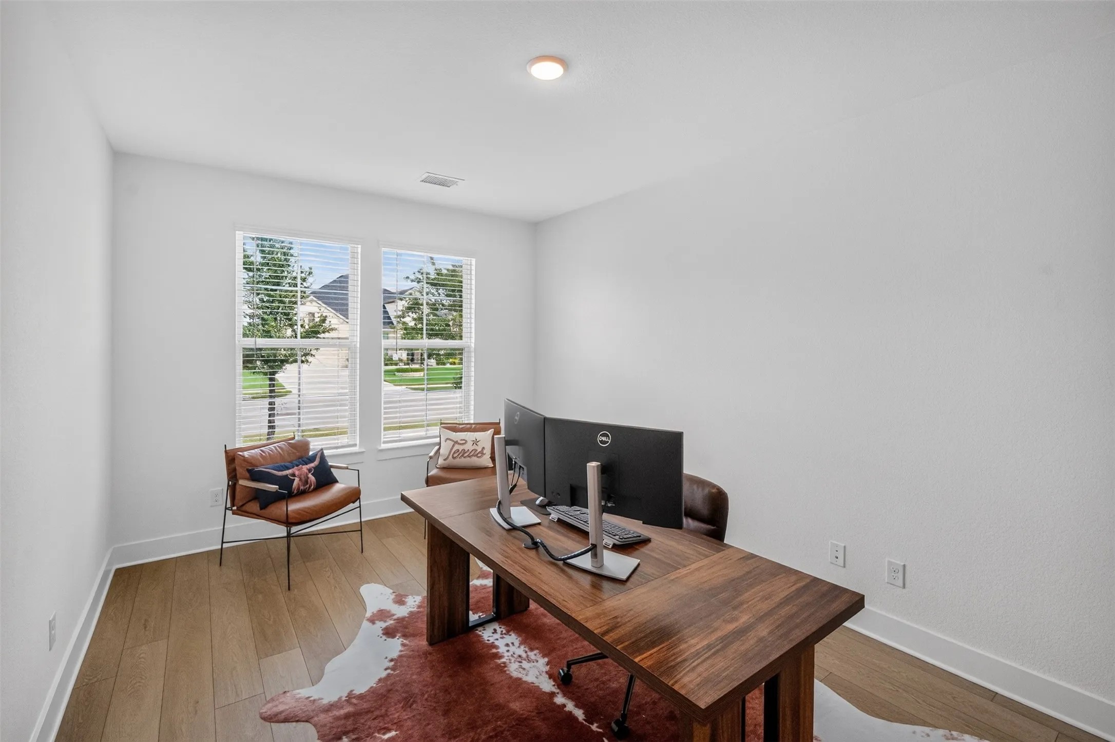 Bright room with two windows, wood-finish flooring, and a recessed ceiling light