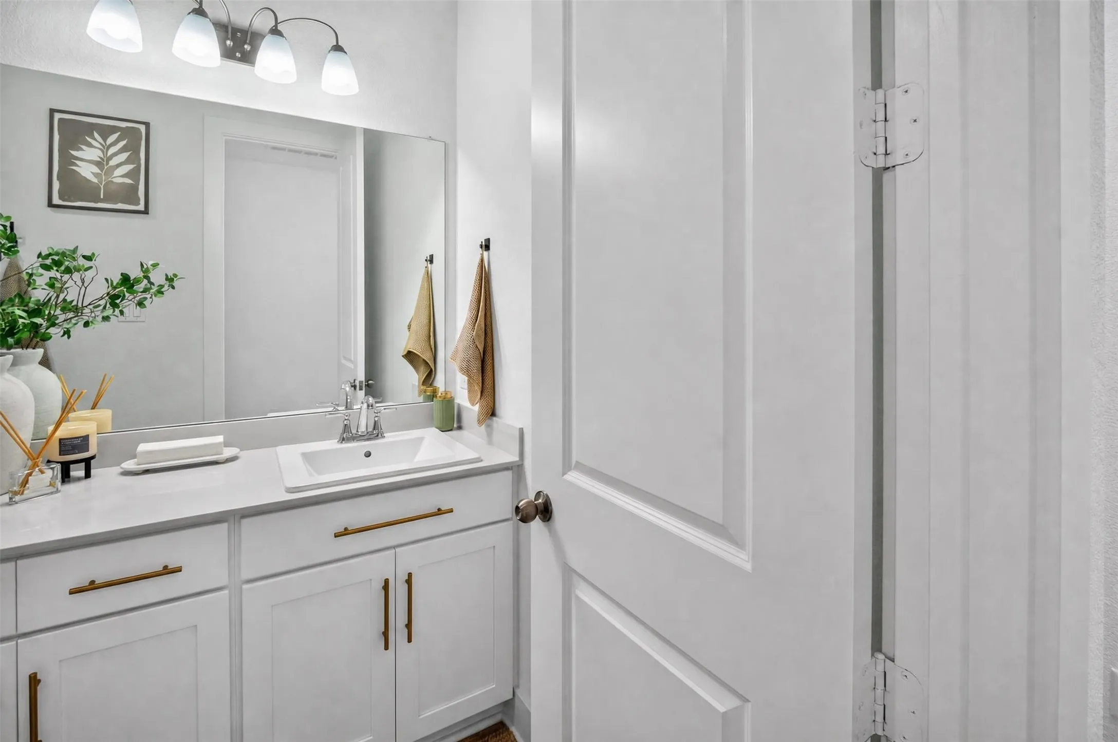 Spacious vanity with undermount sink, brass hardware, and a large wall-mounted mirror
