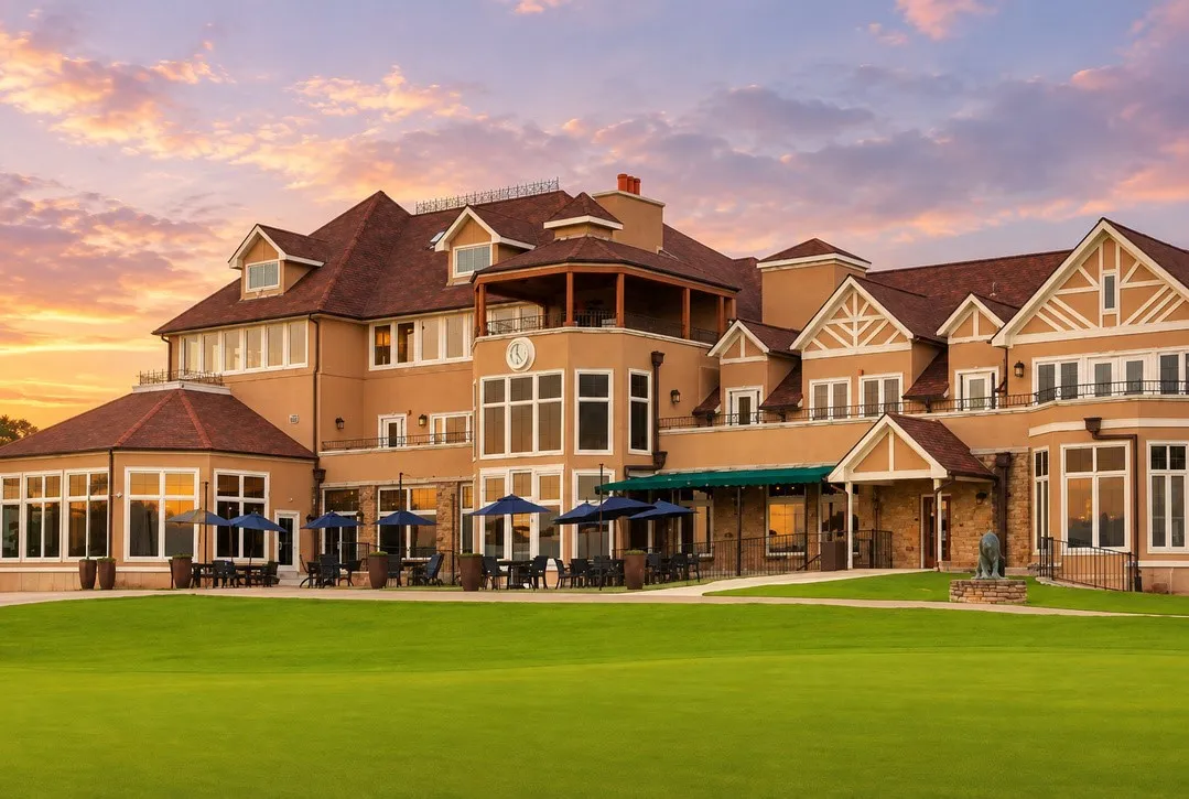 Expansive structure featuring multiple gabled roofs, stone accents, numerous windows, and an outdoor patio area