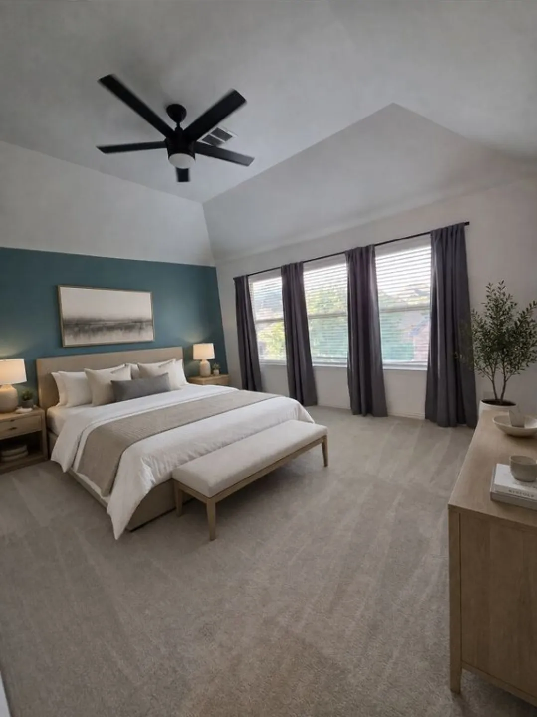 Vaulted ceiling, ceiling fan with integrated lighting, three windows with blinds and drapery, neutral carpet, and a feature wall