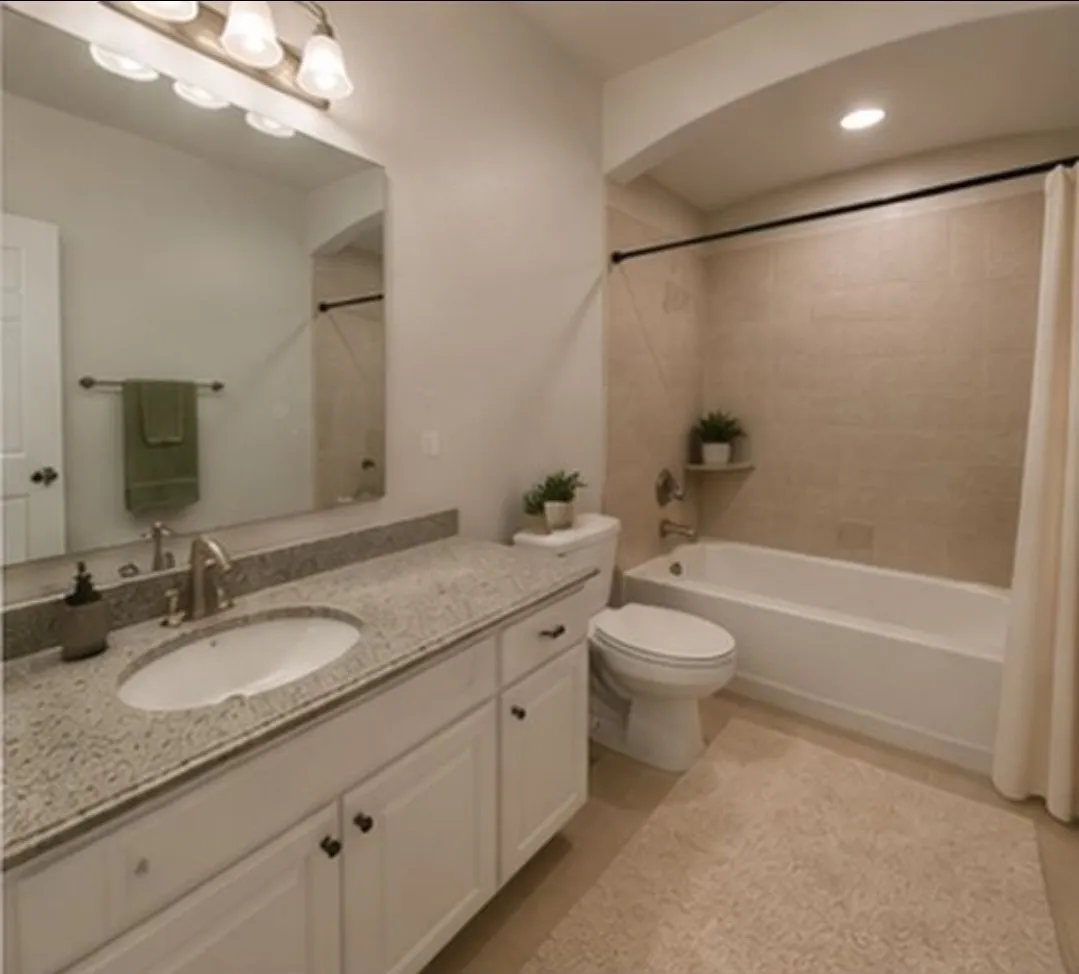 Vanity with integrated sink and stone-finish countertop, white cabinetry with dark hardware, full-width wall mirror, and a built-in bathtub with tiled surround