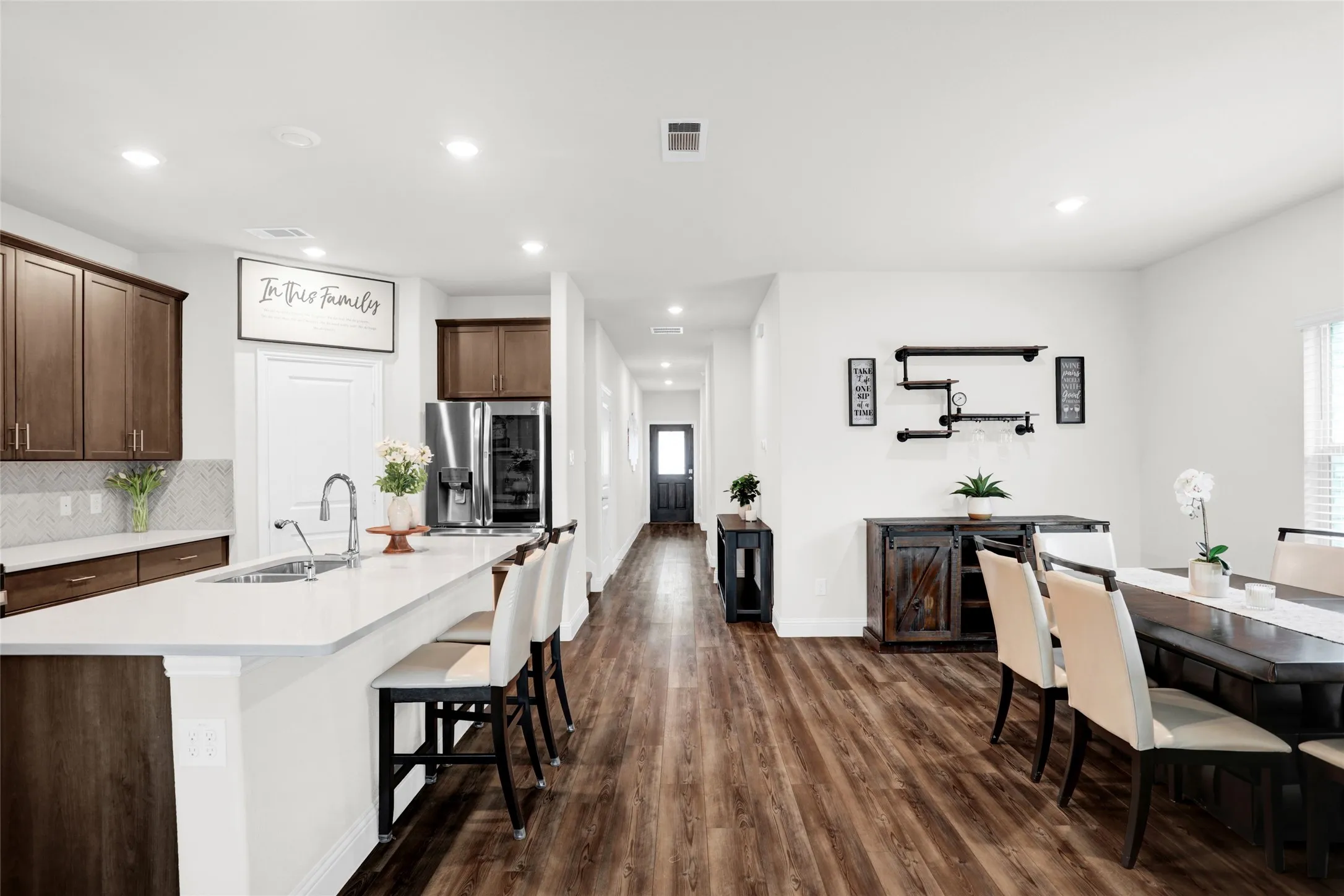 Kitchen featuring dark brown cabinetry, dark wood finished floors, recessed lighting, a breakfast bar, and backsplash