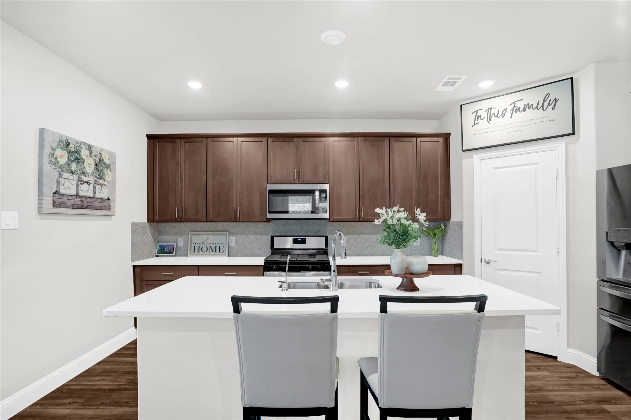 Kitchen with an island with sink, a breakfast bar area, tasteful backsplash, appliances with stainless steel finishes, and dark wood finished floors