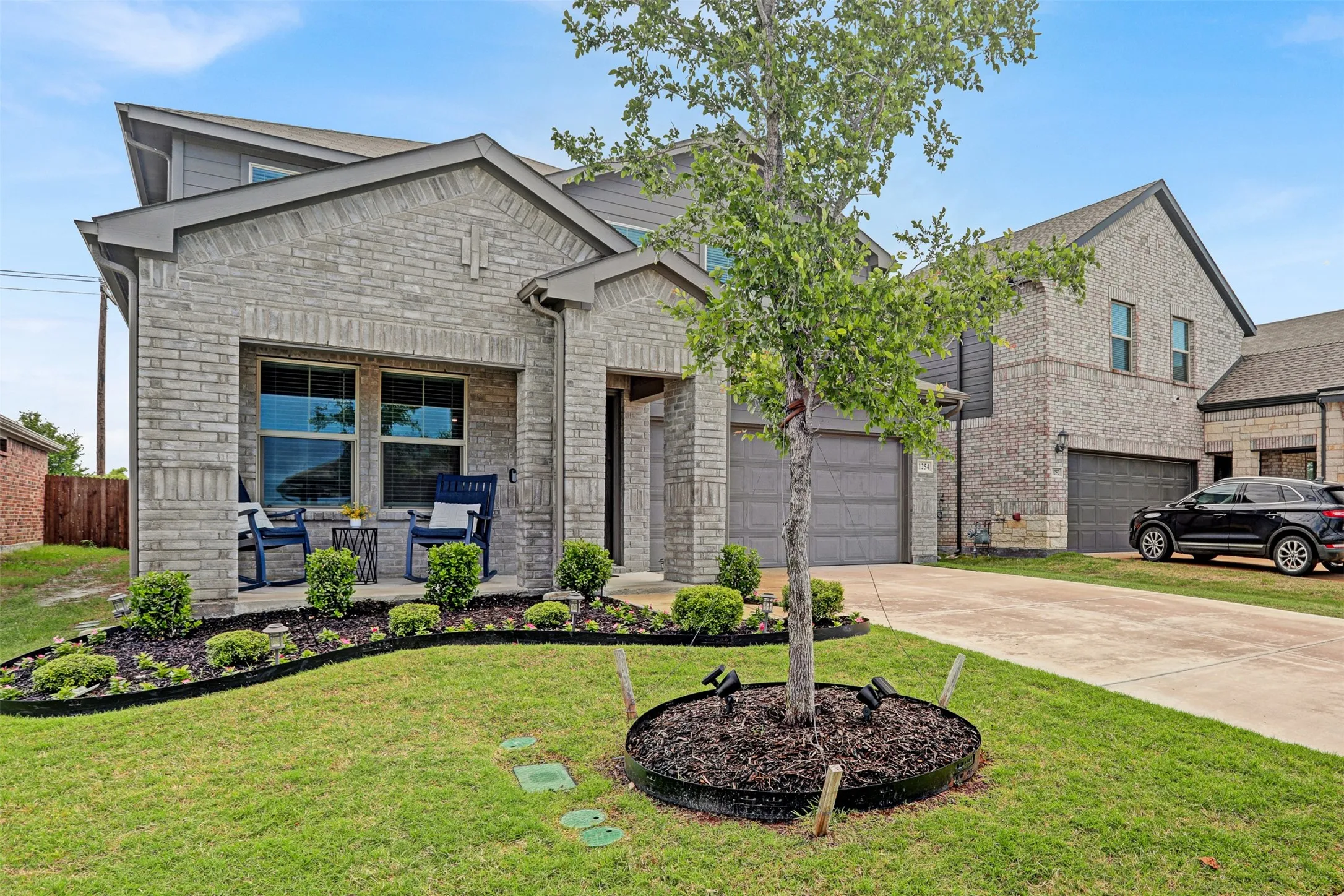 View of front of property featuring driveway, brick siding, a front lawn, and stone siding