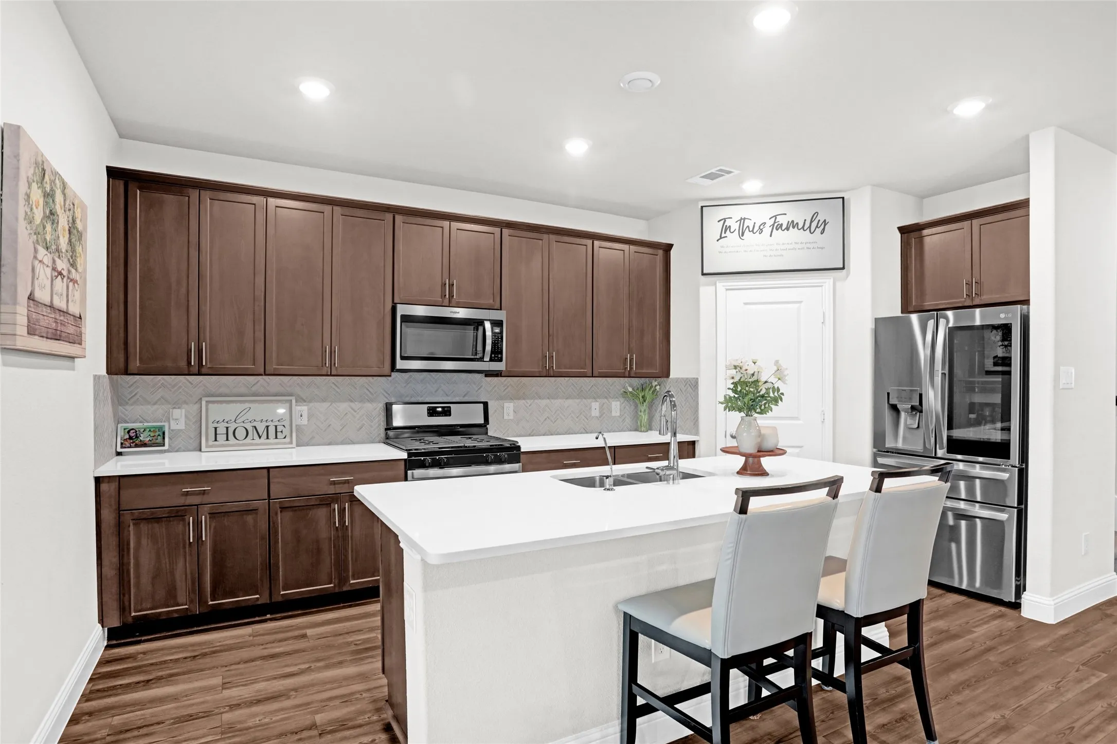 Kitchen with backsplash, stainless steel appliances, a breakfast bar, a center island with sink, and recessed lighting