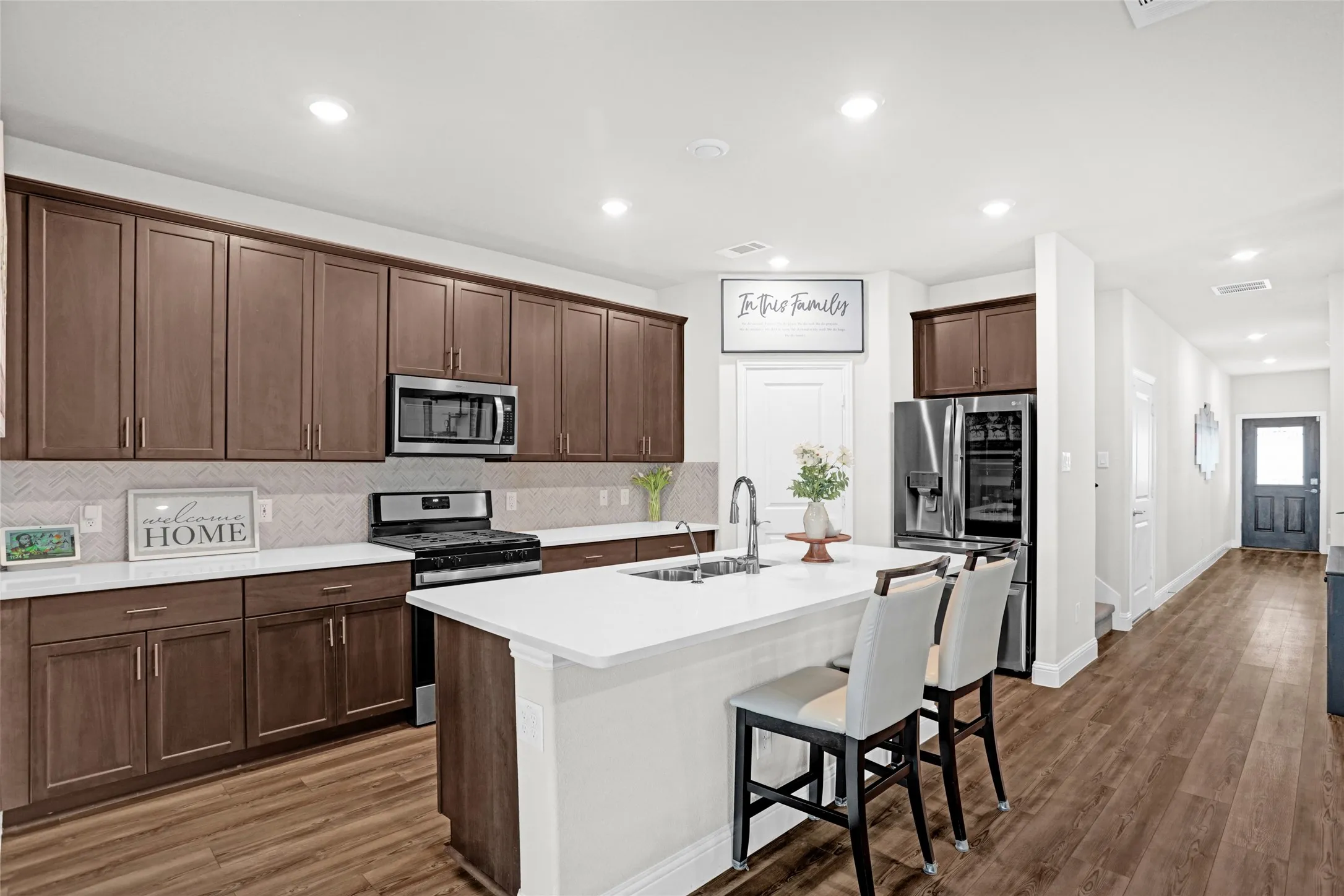 Kitchen featuring decorative backsplash, stainless steel appliances, a breakfast bar area, recessed lighting, and dark wood-type flooring