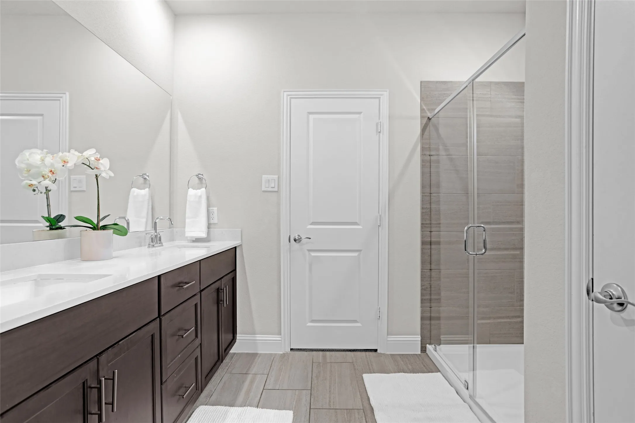 Full bath featuring a shower stall, double vanity, and wood tiled floors