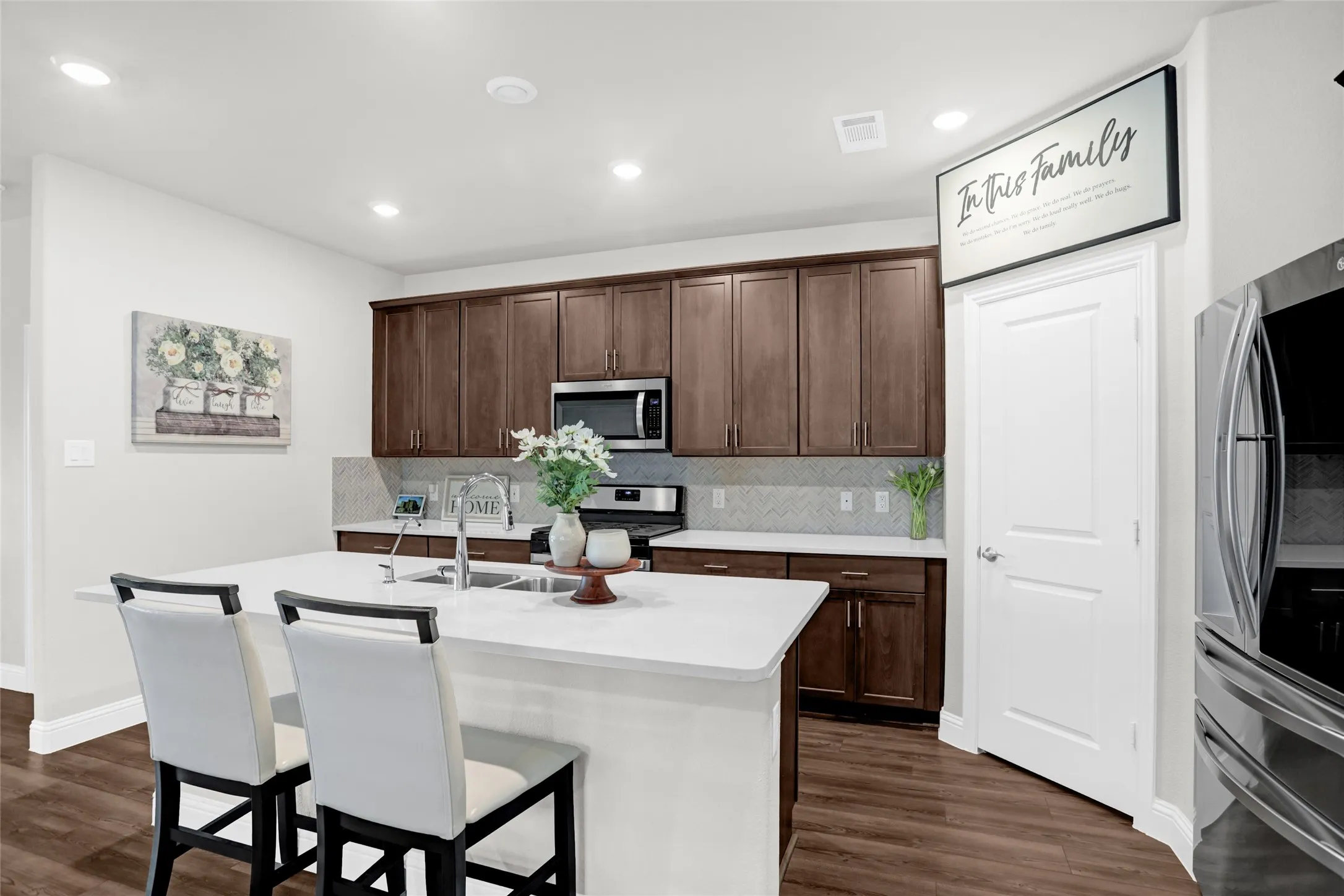 Kitchen with tasteful backsplash, dark wood-type flooring, a kitchen breakfast bar, stainless steel appliances, and recessed lighting