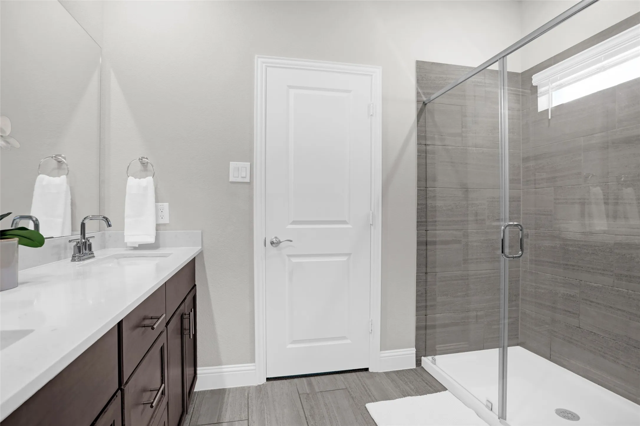 Bathroom featuring double vanity, a shower stall, and light wood-style floors