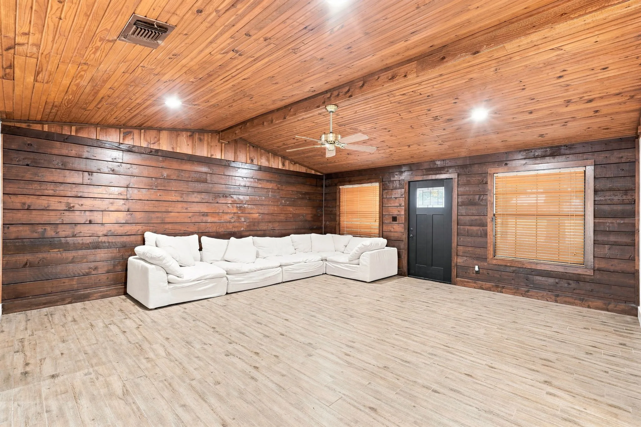 Wood-paneled walls and ceiling, vaulted ceiling, wood-finish flooring, ceiling fan, and recessed lighting