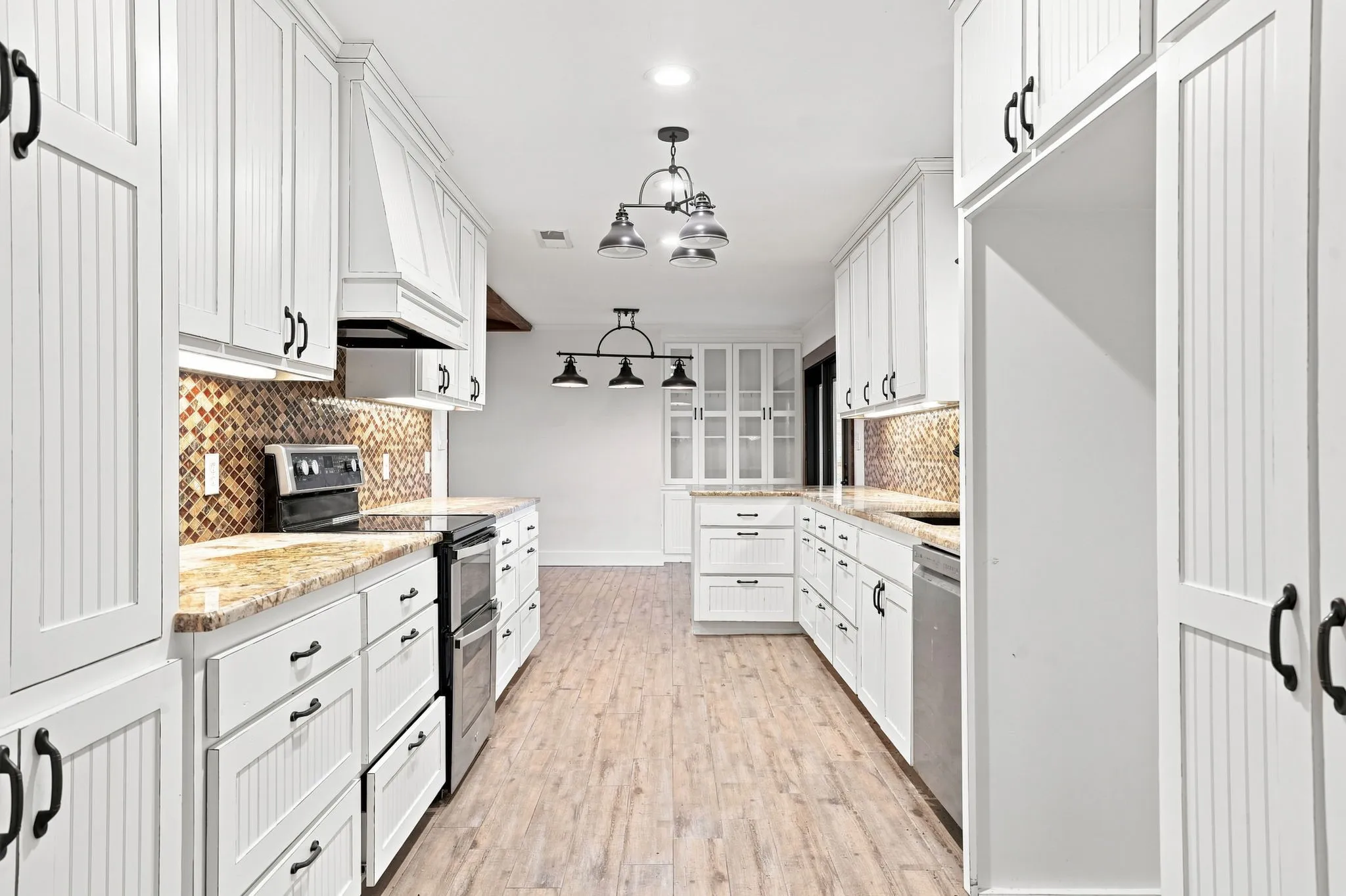 White cabinetry with beadboard accents, granite countertops, mosaic tile backsplash, stainless steel appliances, and wood-finish flooring